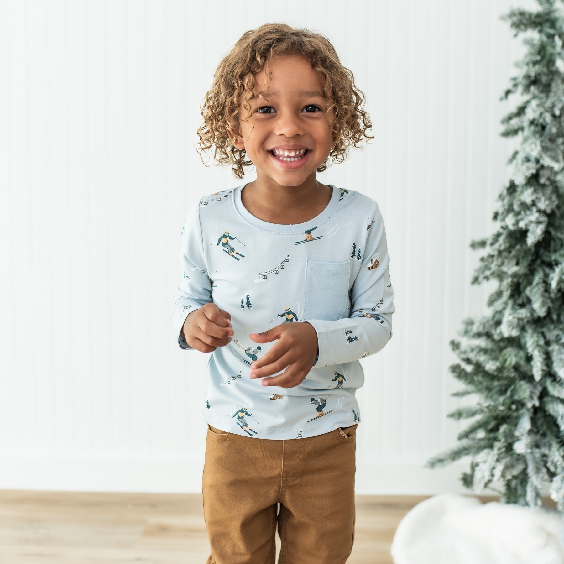 Young smiling boy wearing the Long Sleeve Toddler Crew Neck Tee in Ski with bronze colored pants