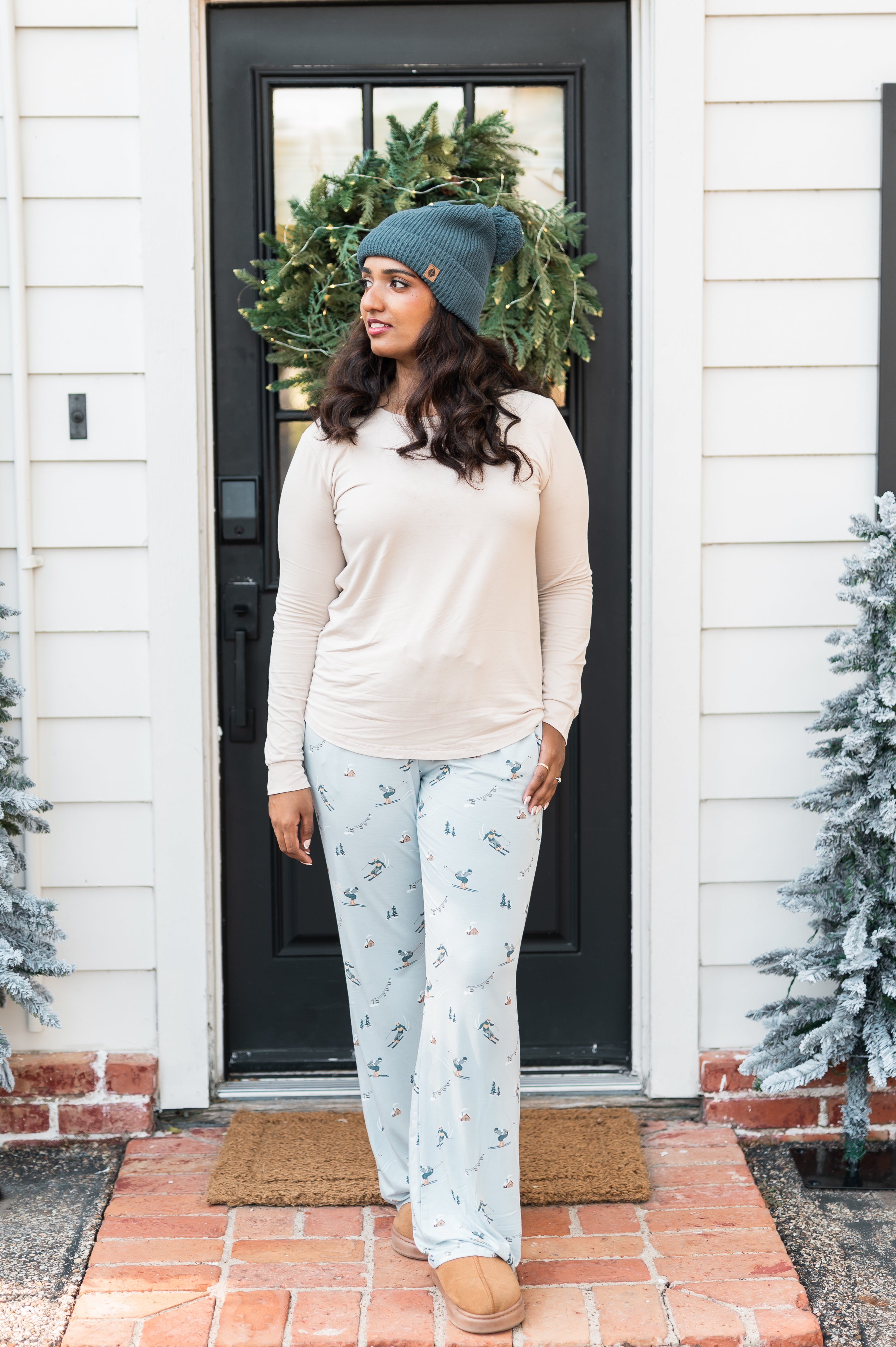 Female model standing at a front door wearing the Women's Lounge Pants in Ski paired with a cream colored shirt and Atlantic beanie