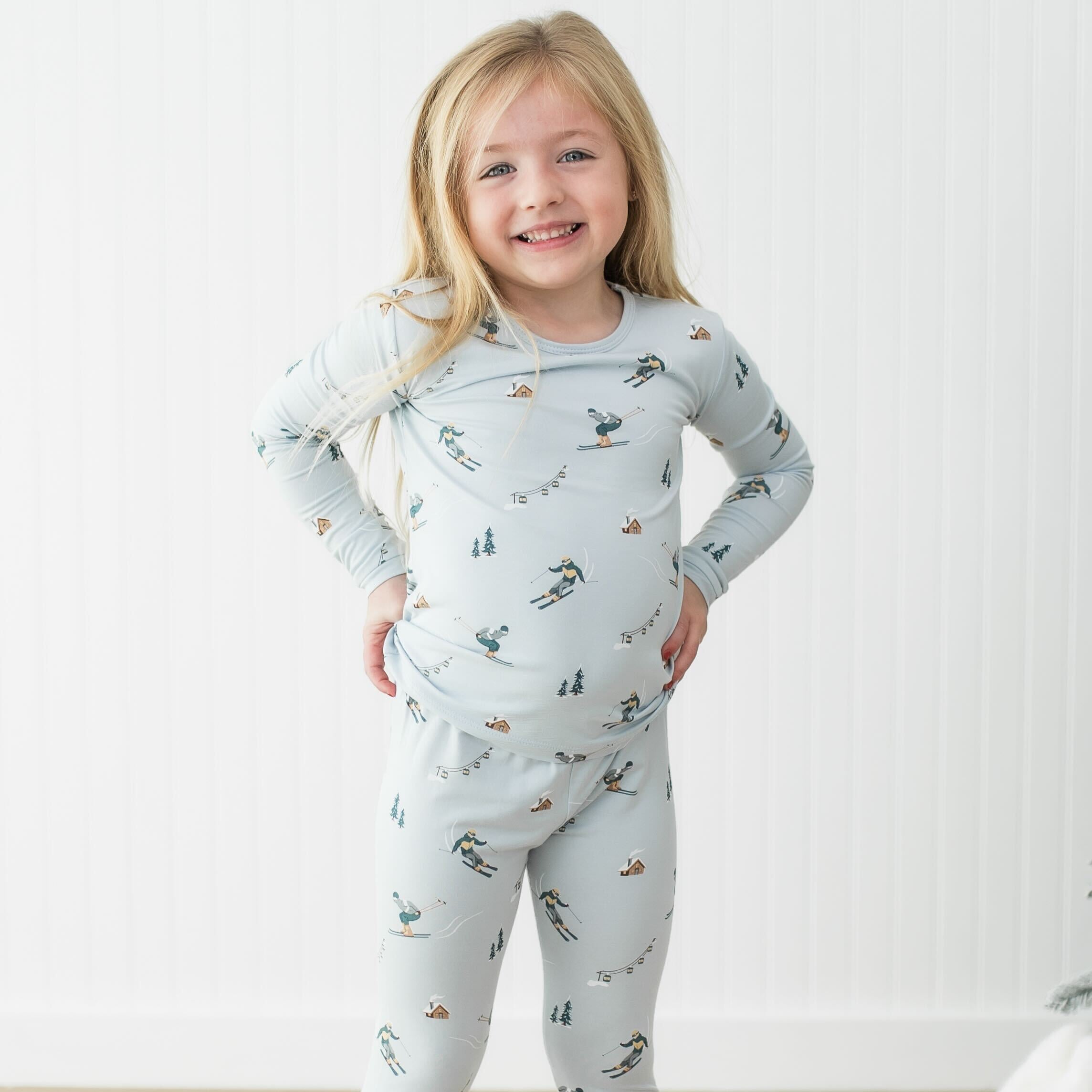 Toddler modeling a long sleeve pajama set with a Ski printed pattern 