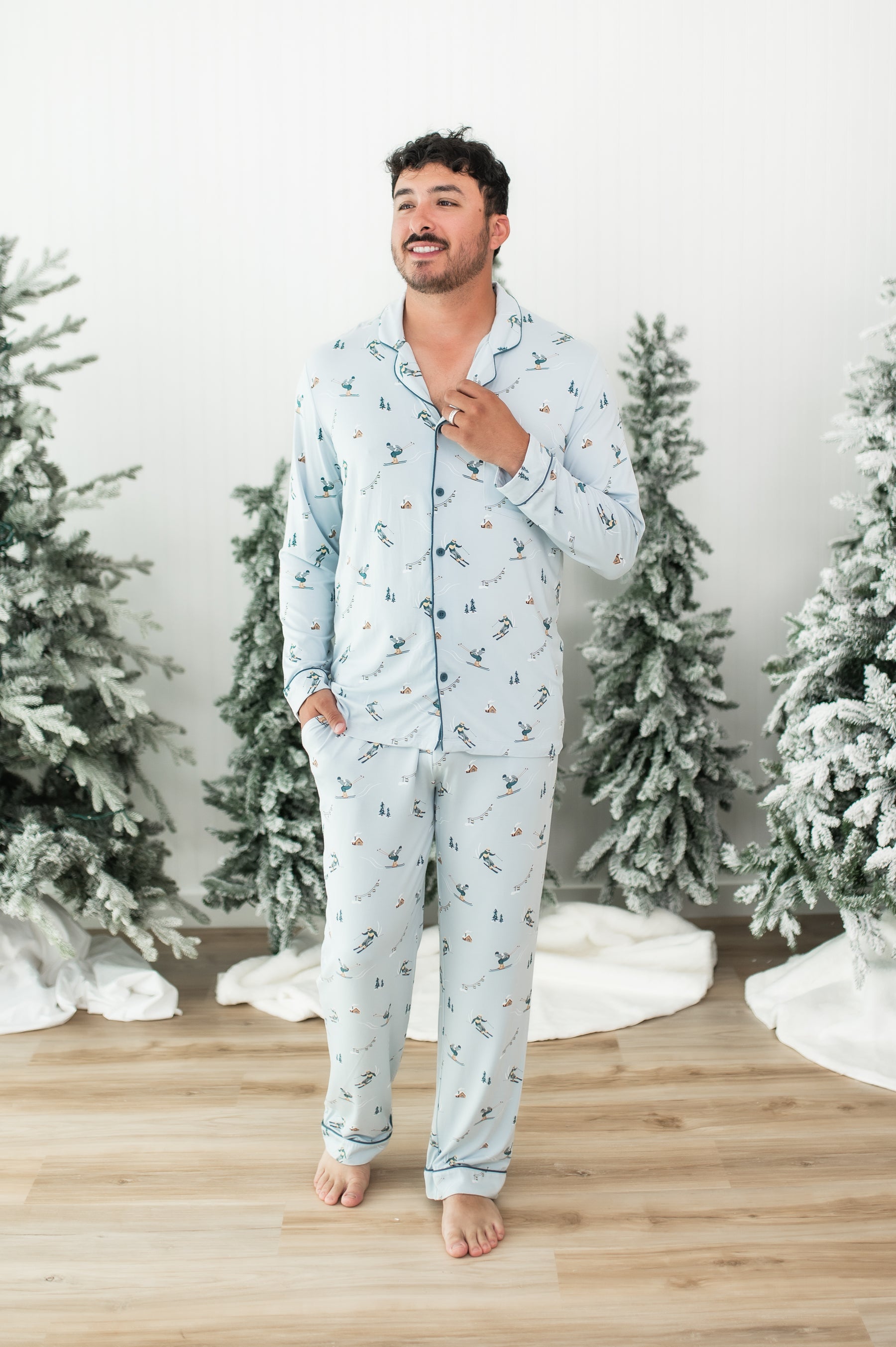Smiling male model walking wearing the Men's Long Sleeve Pajama Set in Ski with one hand in the pants pocket and the other on the neck collar of the shirt