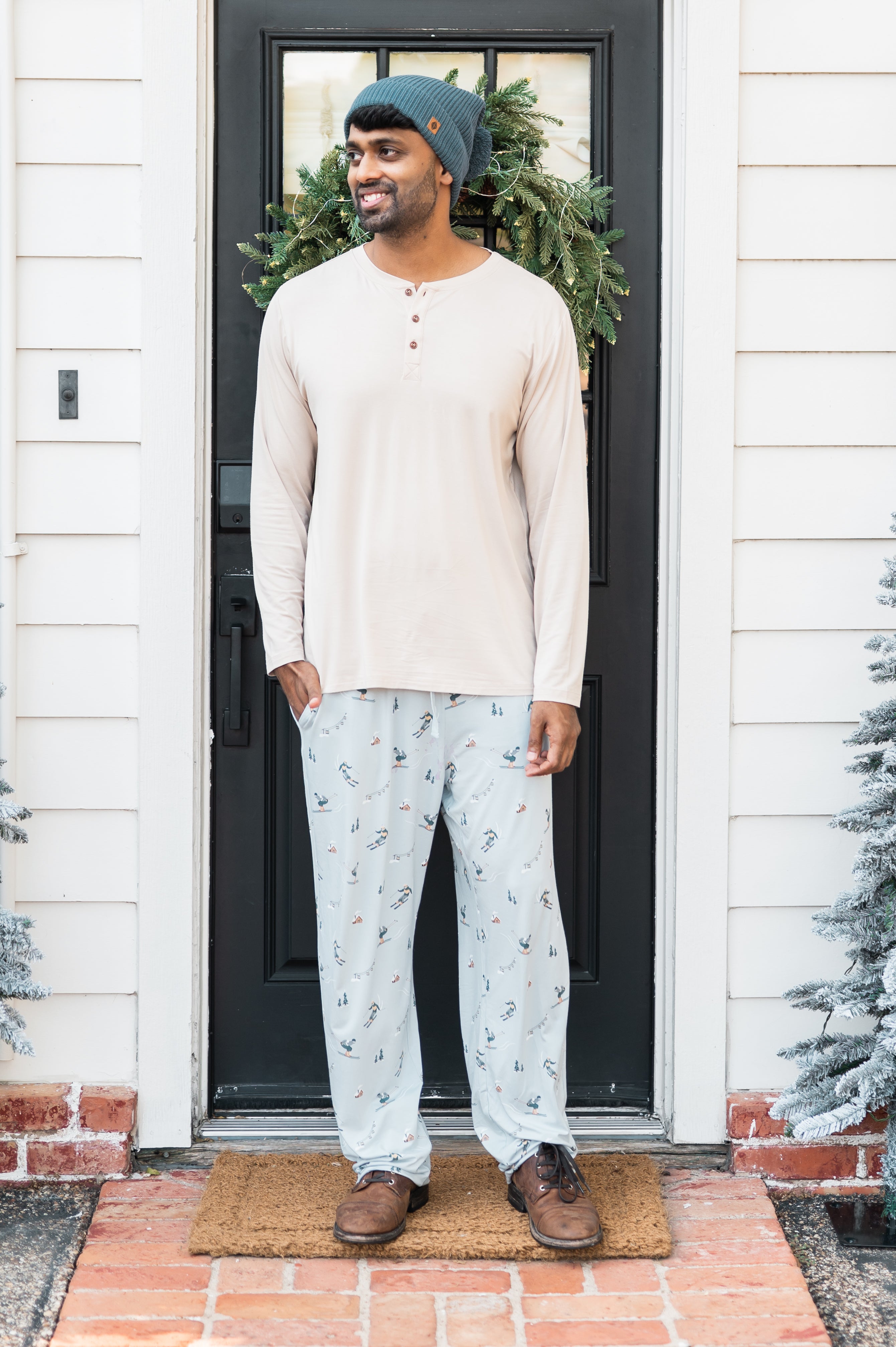 Male model standing in front of a doorway wearing the Men's Lounge Pants in Ski paired with a cream shirt
