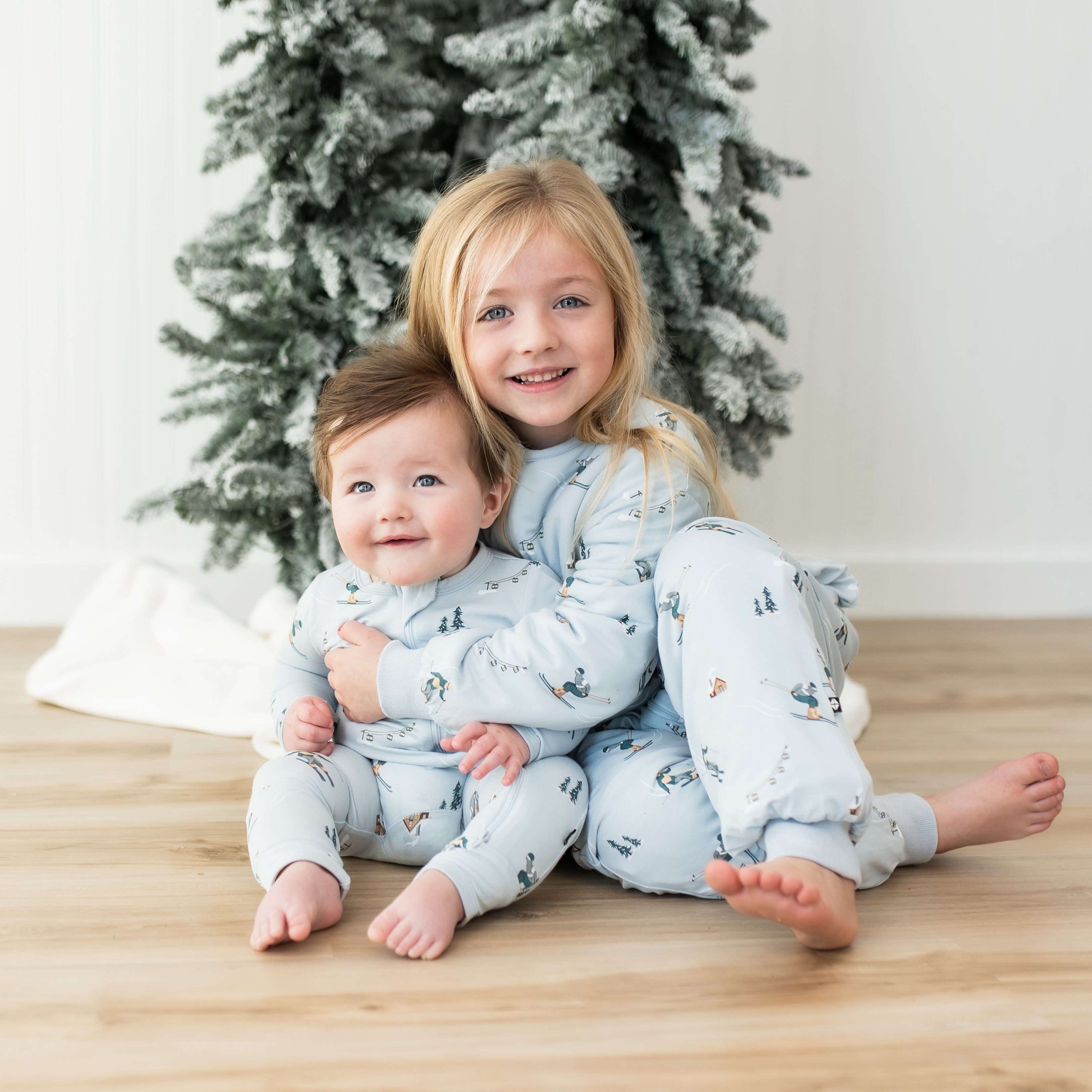 Brother and sister sitting on the floor both wearing Ski items