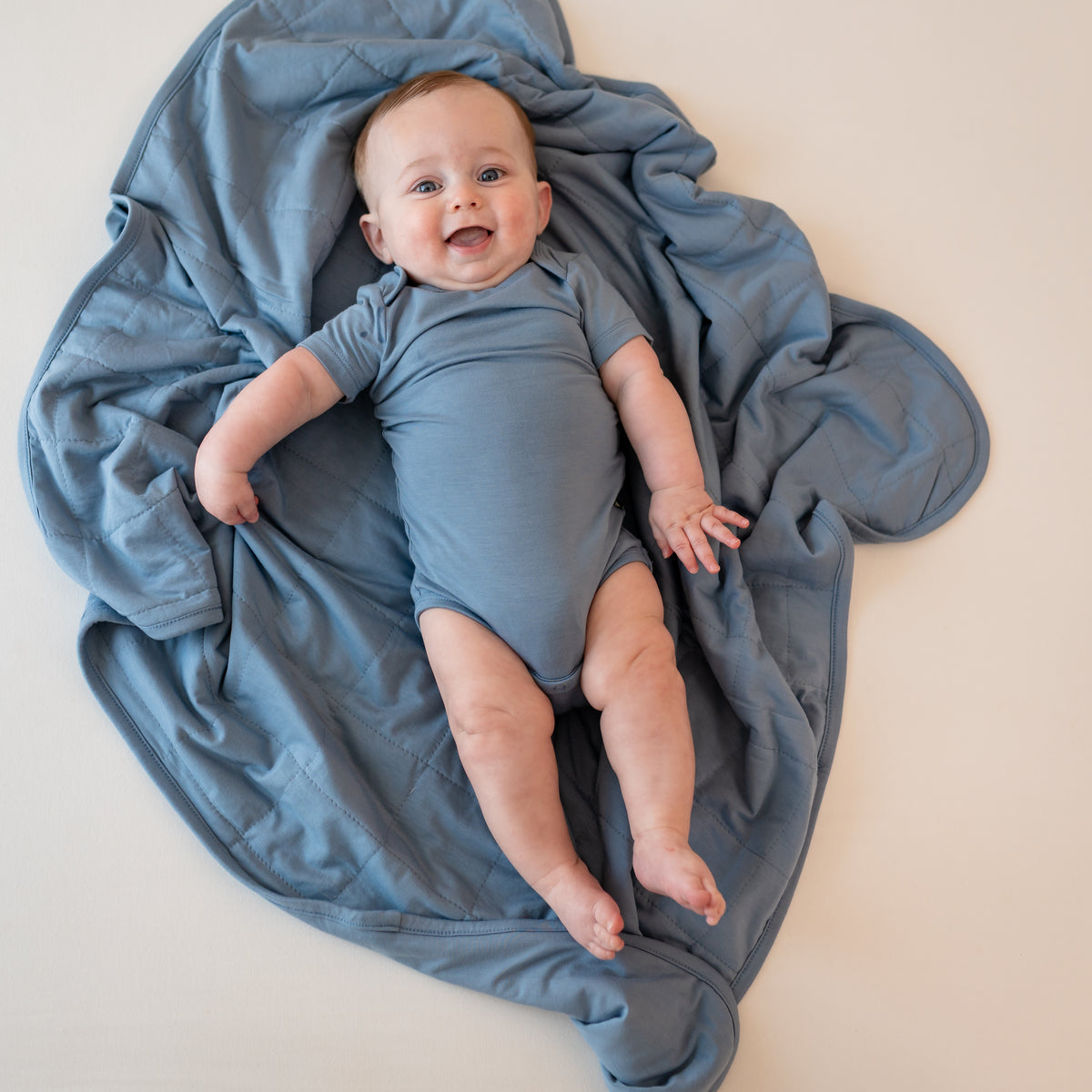 Baby in Slate Bodysuit laying on Baby Blanket in Slate 1.0