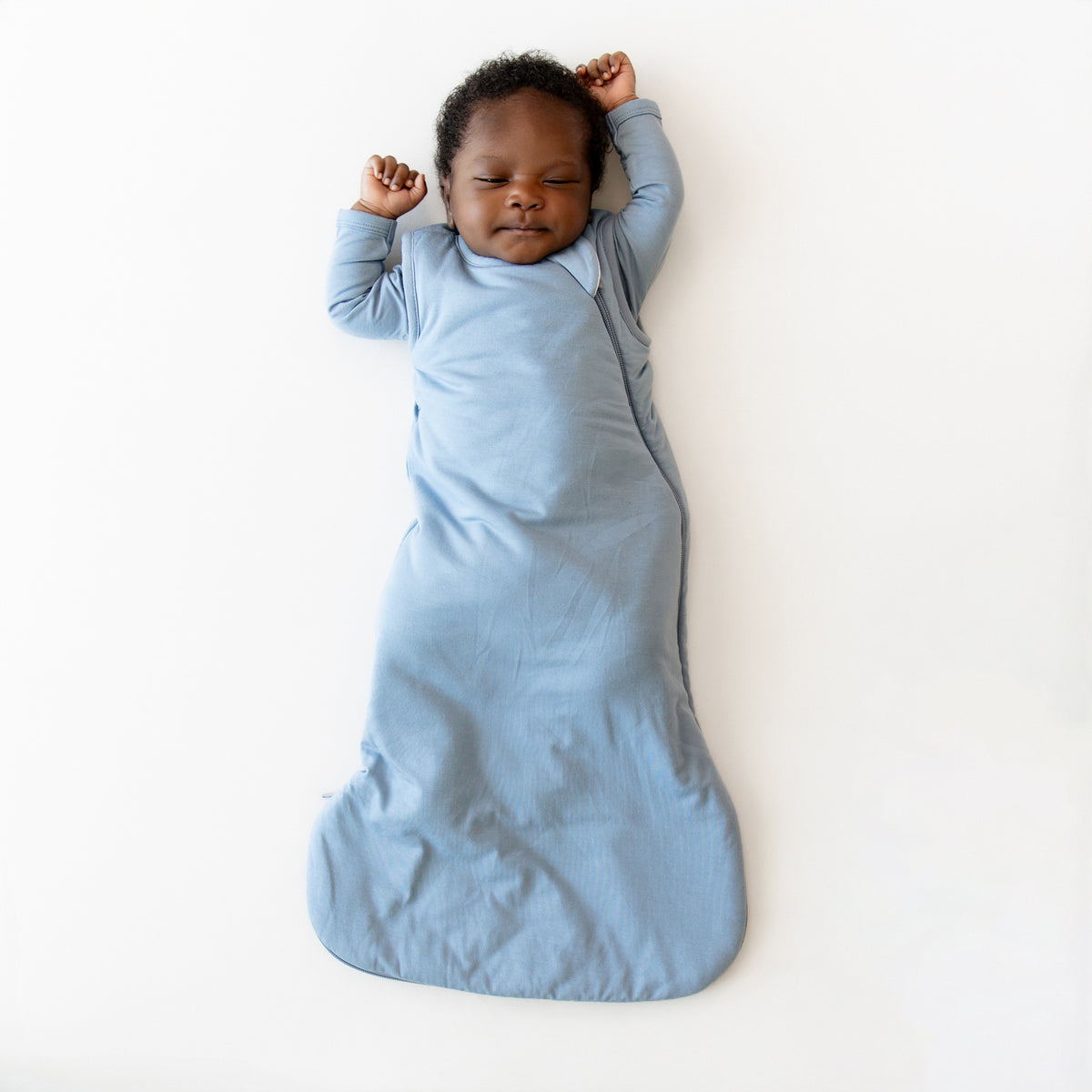 Baby sleeping in a blue sleep bag on a white background