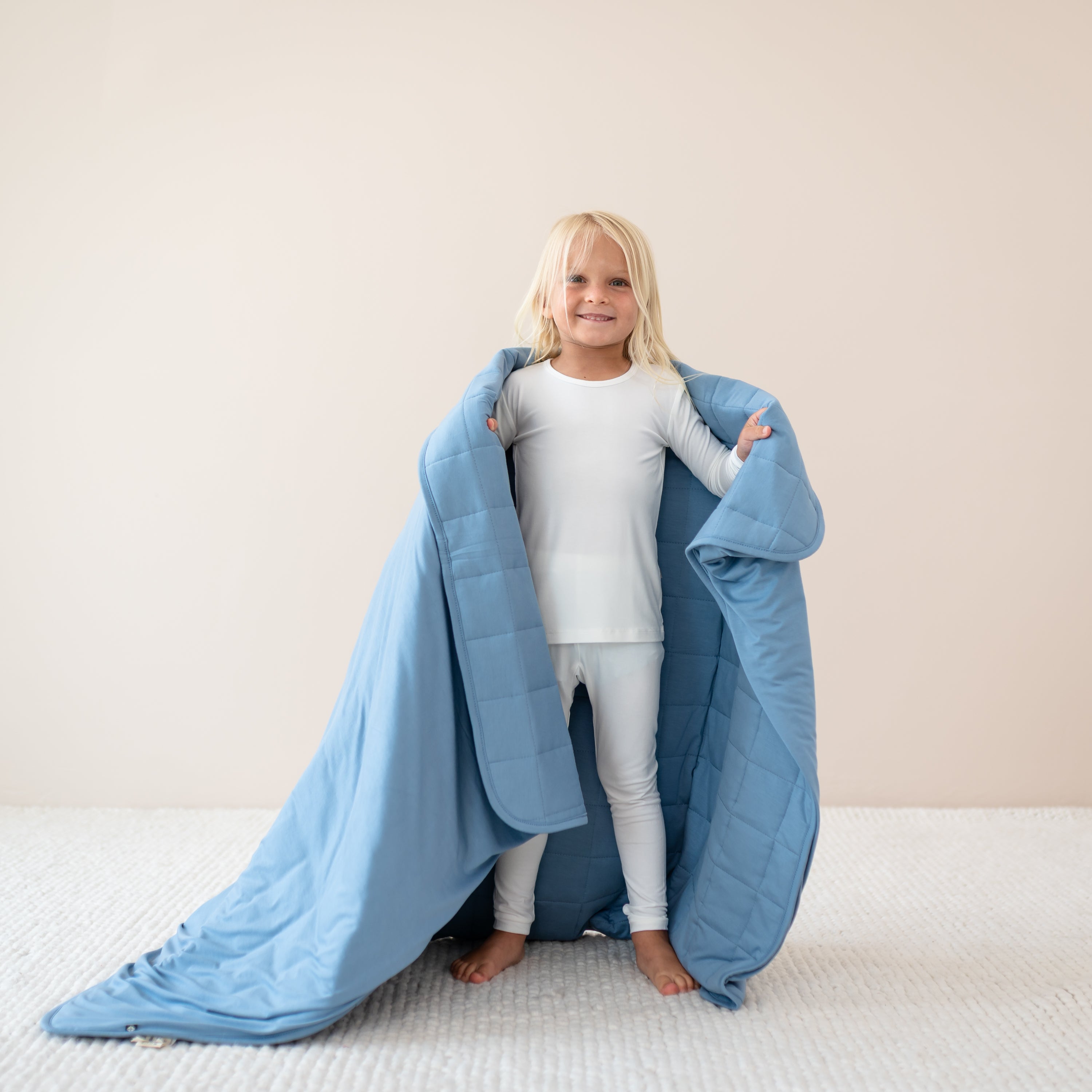 Child holding Youth Blanket in Slate 2.5 wearing cloud long sleeve pajamas