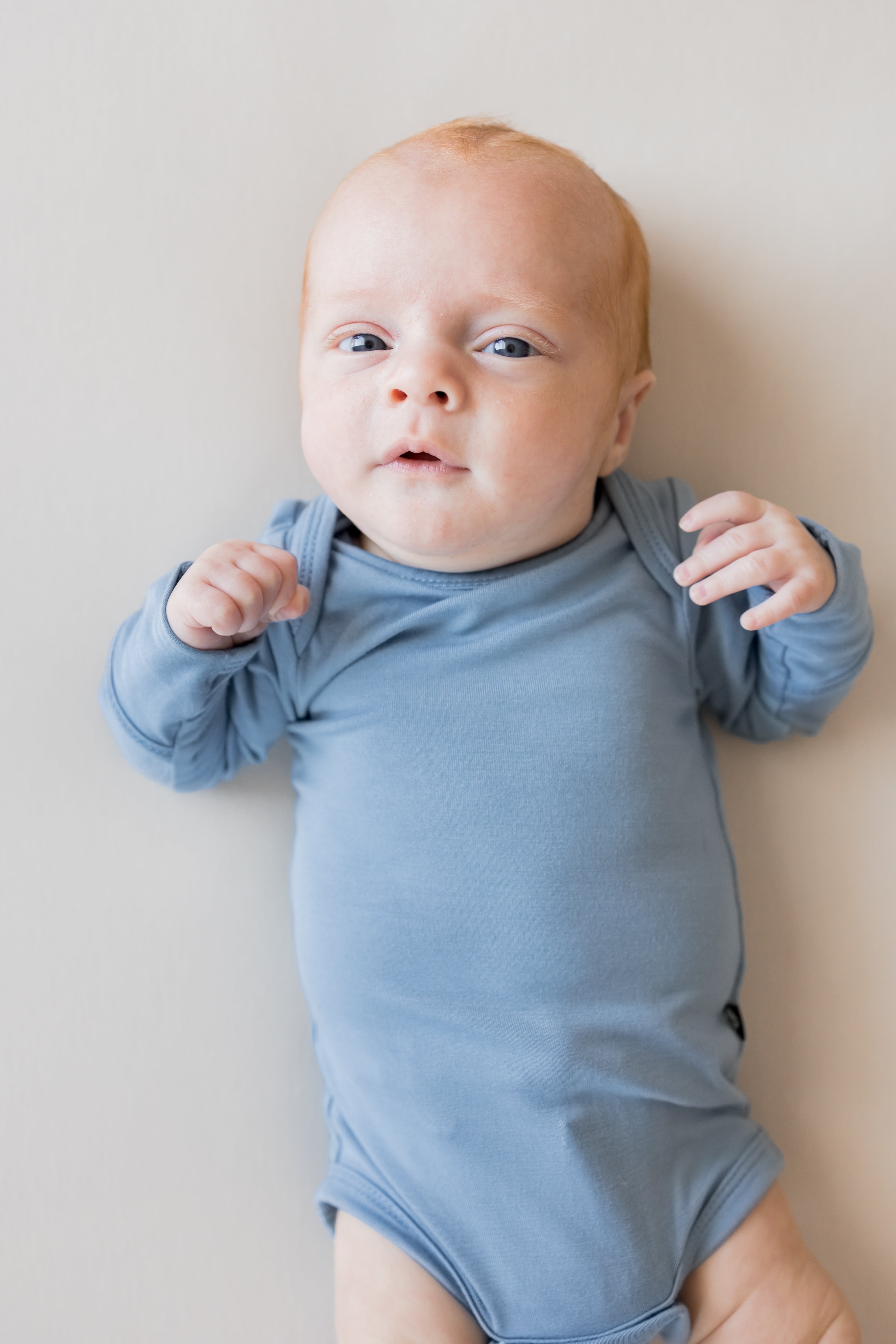 Close up of Baby wearing Long Sleeve Bodysuit in Slate color on a beige background