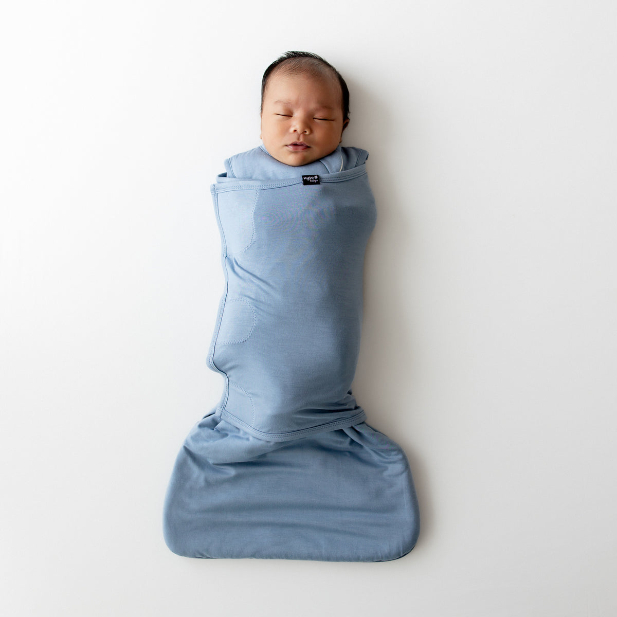 Newborn baby swaddled in a blue swaddler on a white background