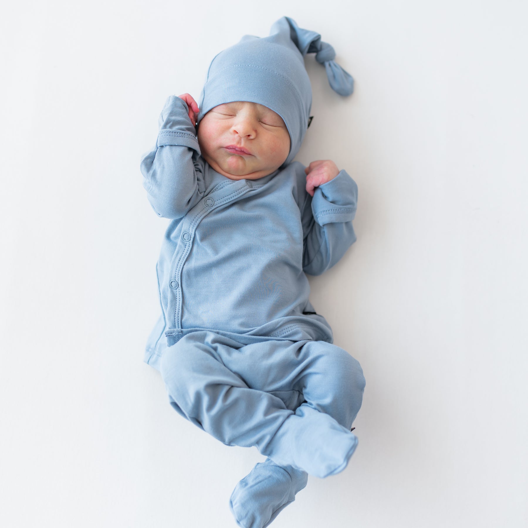 Baby in a take me home set with kimono style top, footie pants and cap in a slate blue