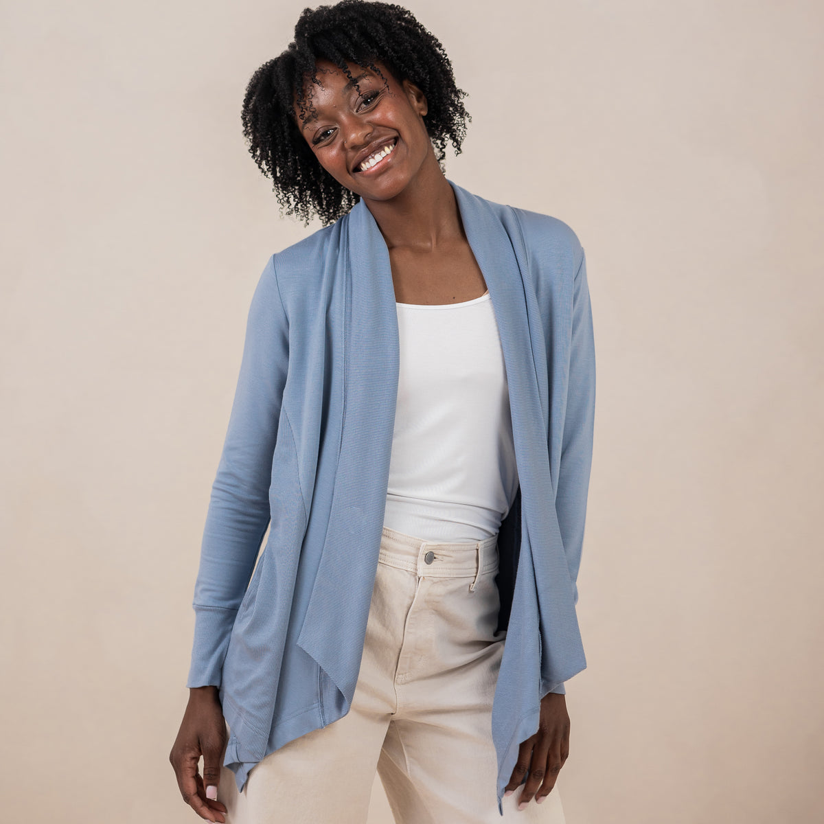 Smiling female model wearing the Women's French Terry Wrap Top in Slate with a white top and cream colored jeans