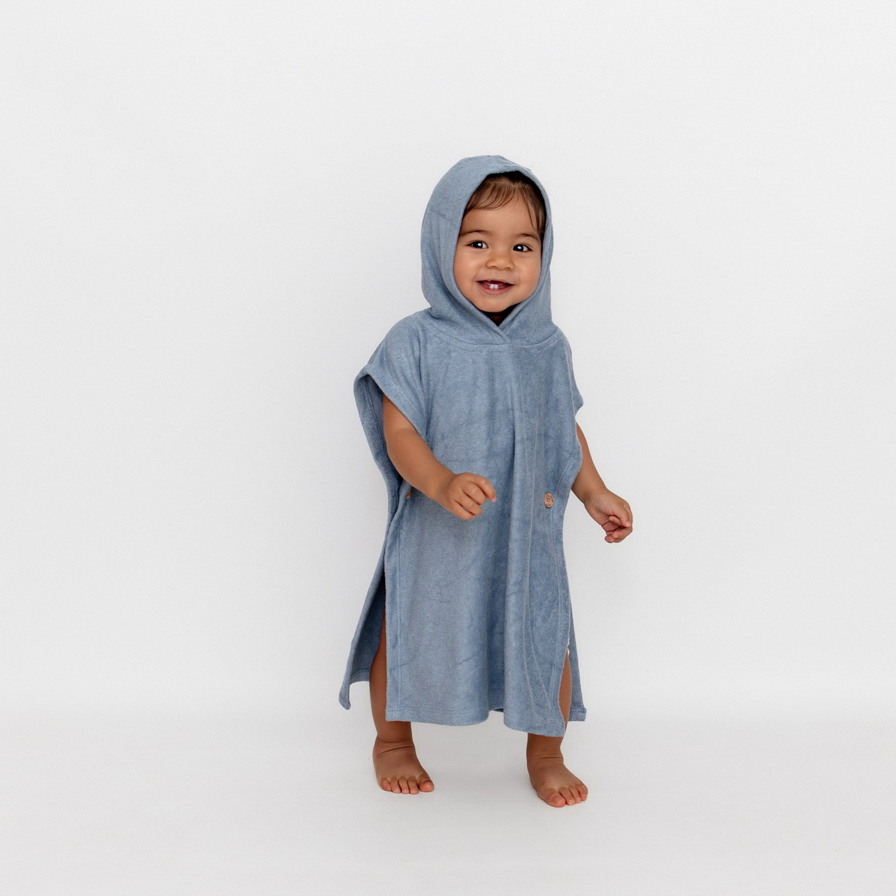 Young girl walking wearing the Swim Poncho in Slate with the hood up 