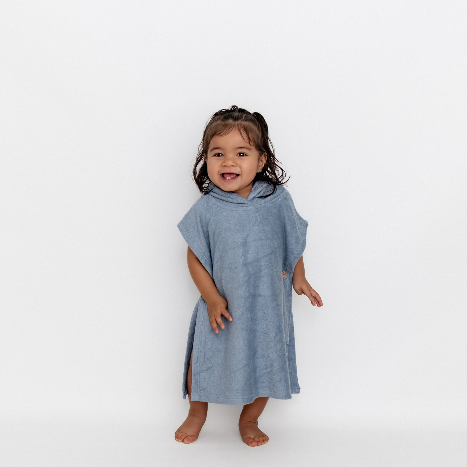 Young girl standing in front of a white background wearing the Swim Poncho in Slate