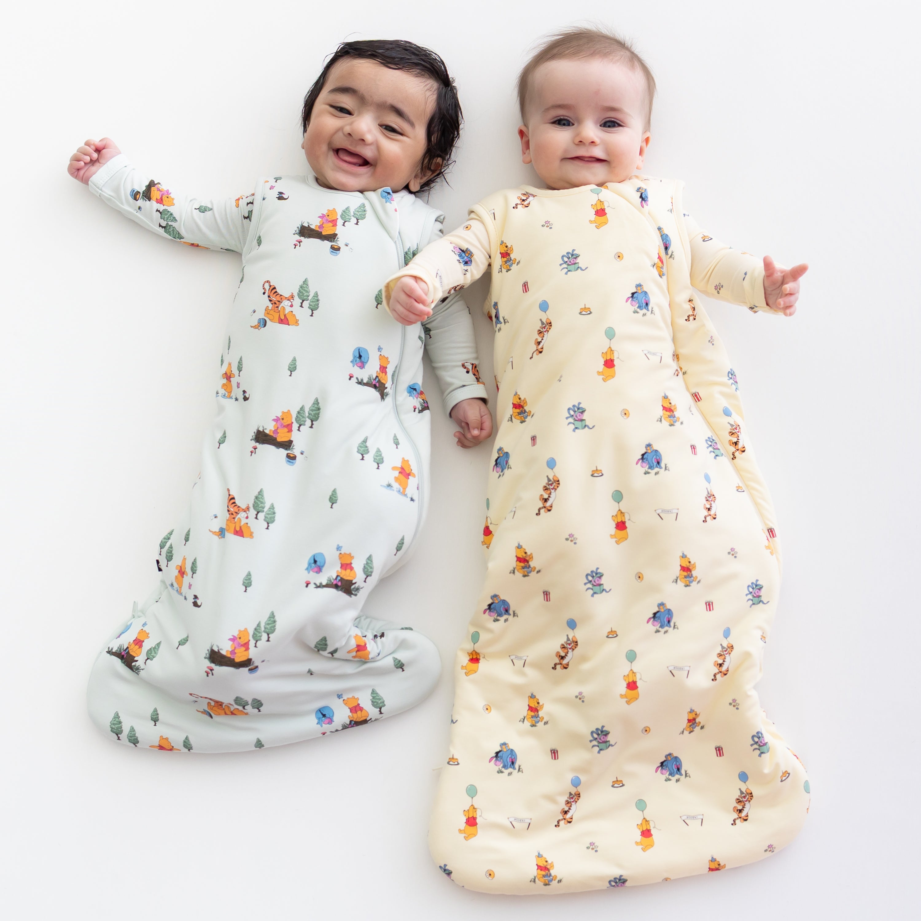 2 babies wearing kyte baby sleep bags in disney's winnie the pooh prints 