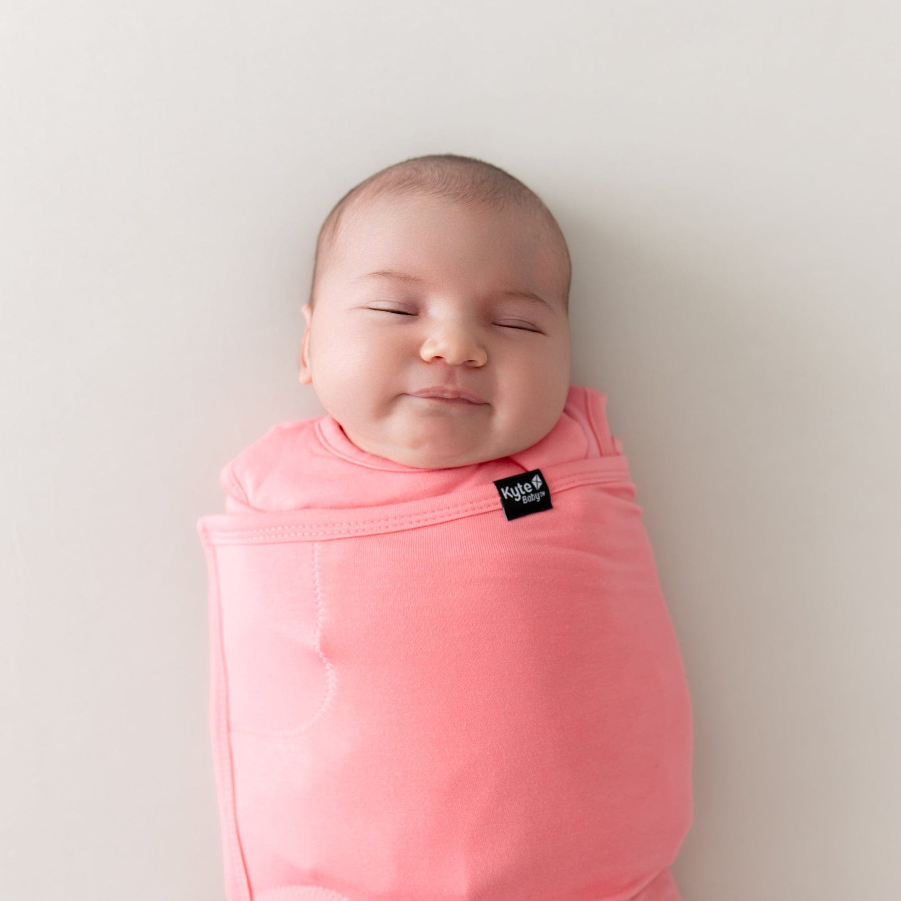 close up of baby wearing sleep bag swaddler in guava