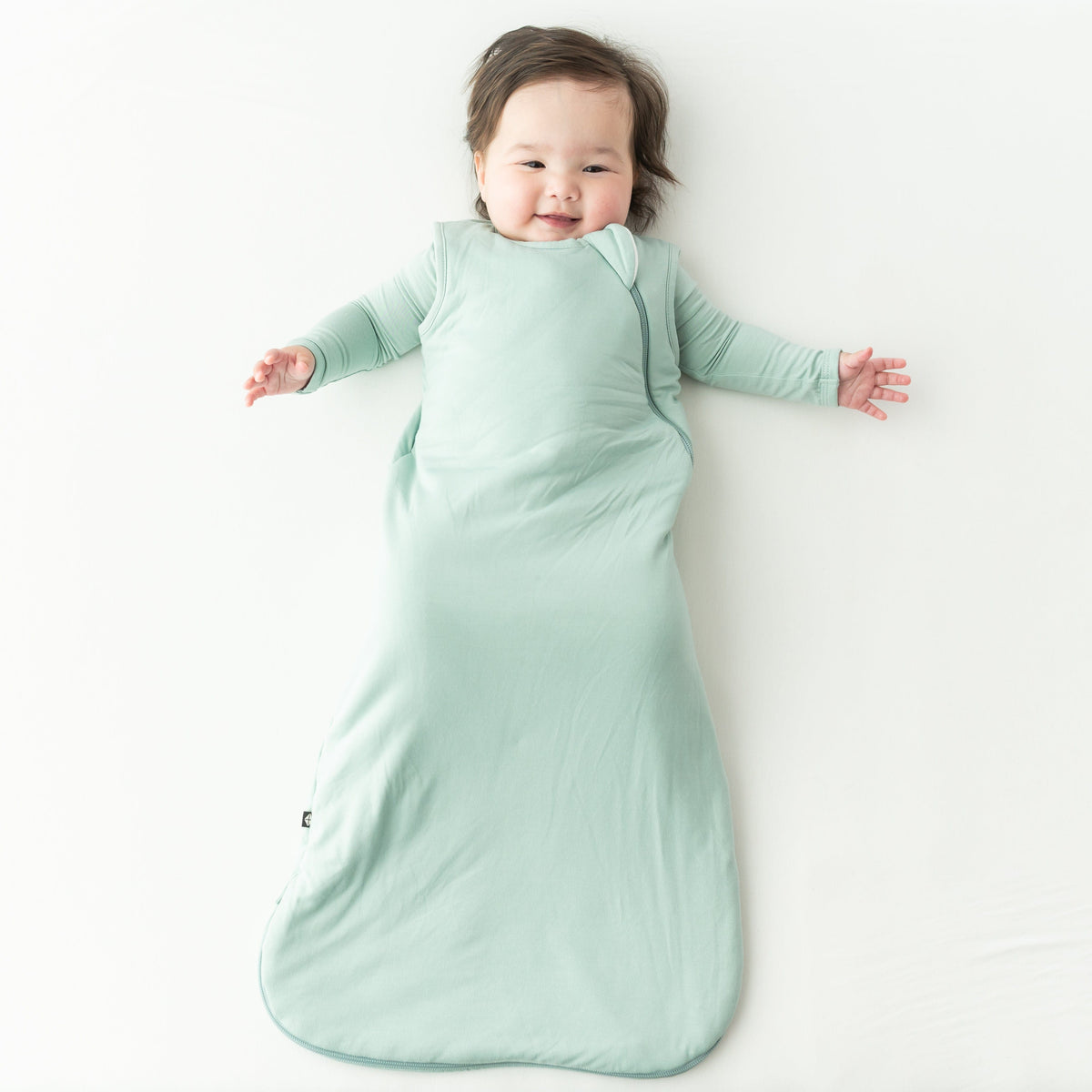 Baby in a light green buttery soft bamboo sleep bag on a white background