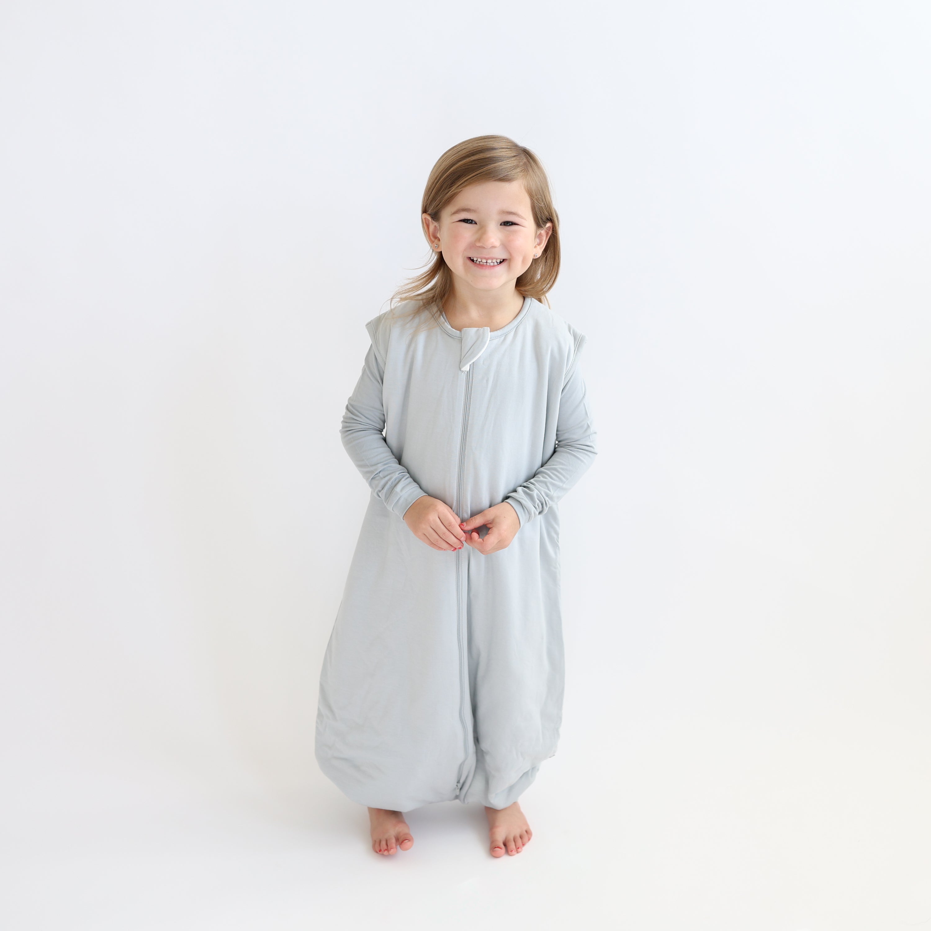 Child wearing a light grey sleep bag walker and matching grey pajama set 