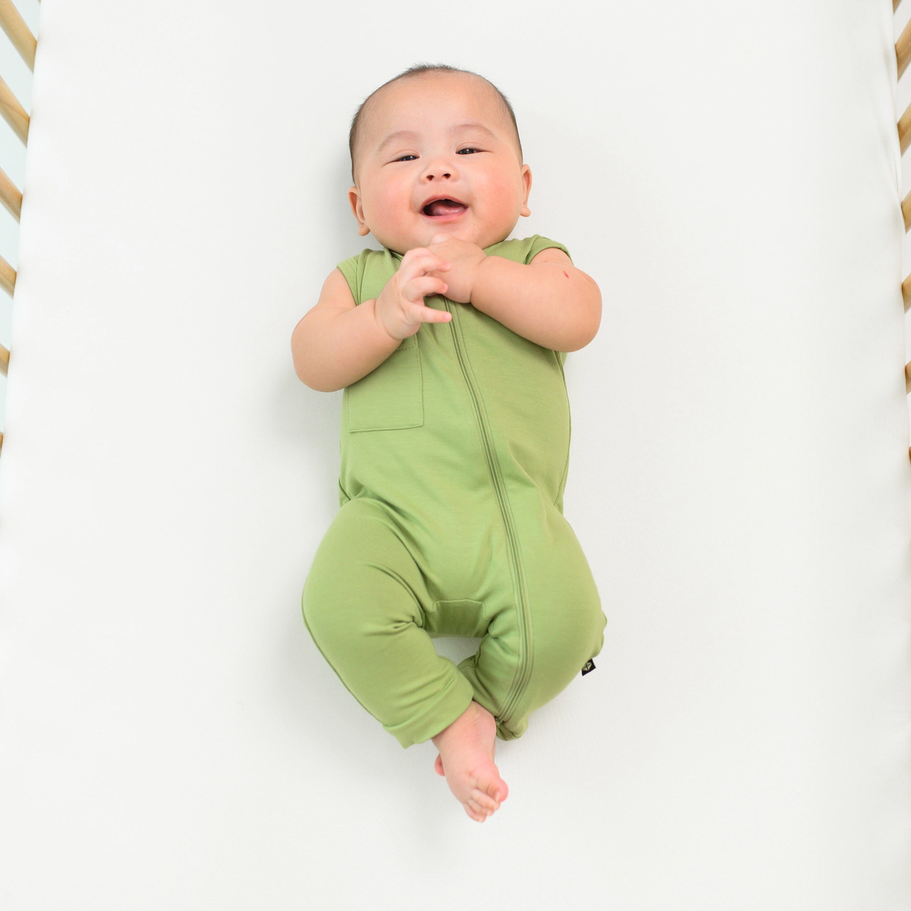 baby smiling wearing zippered sleeveless romper in honu