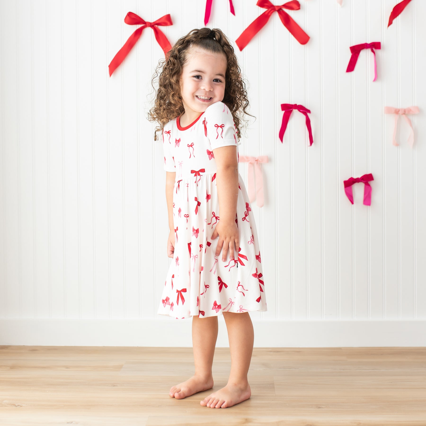 Young girl posing wearing the soft and flowy Twirl Dress in Small Love Bow 