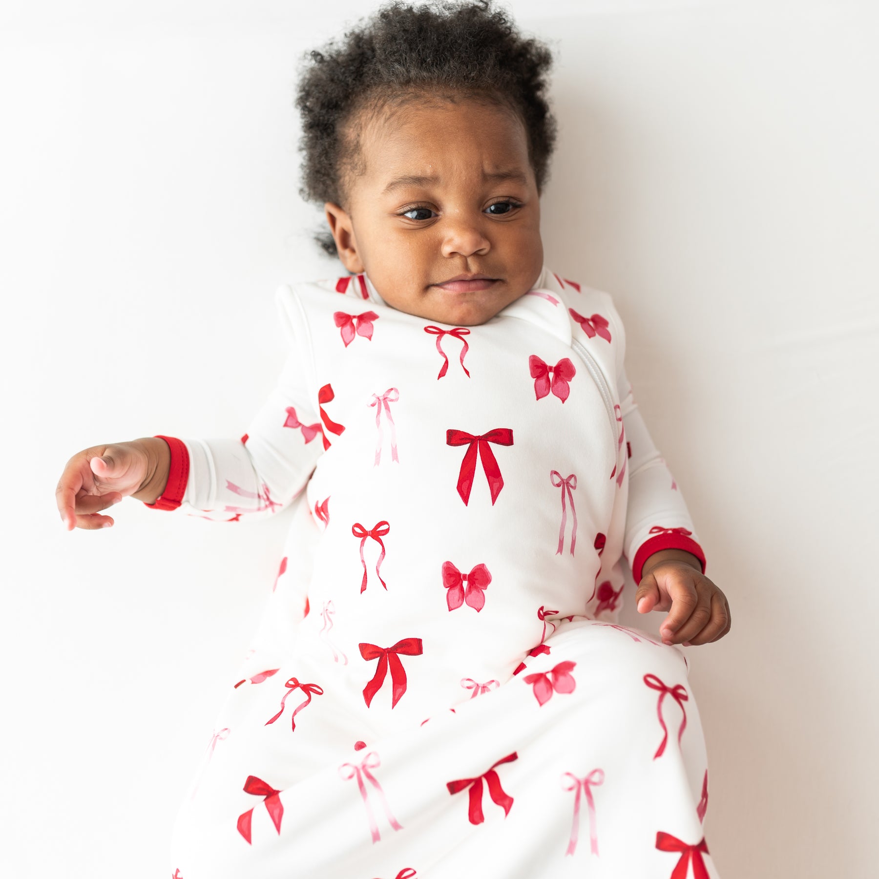 Close up of young toddler wearing the Sleep Bag in Small Love Bow 1.0 with a matching romper on underneath