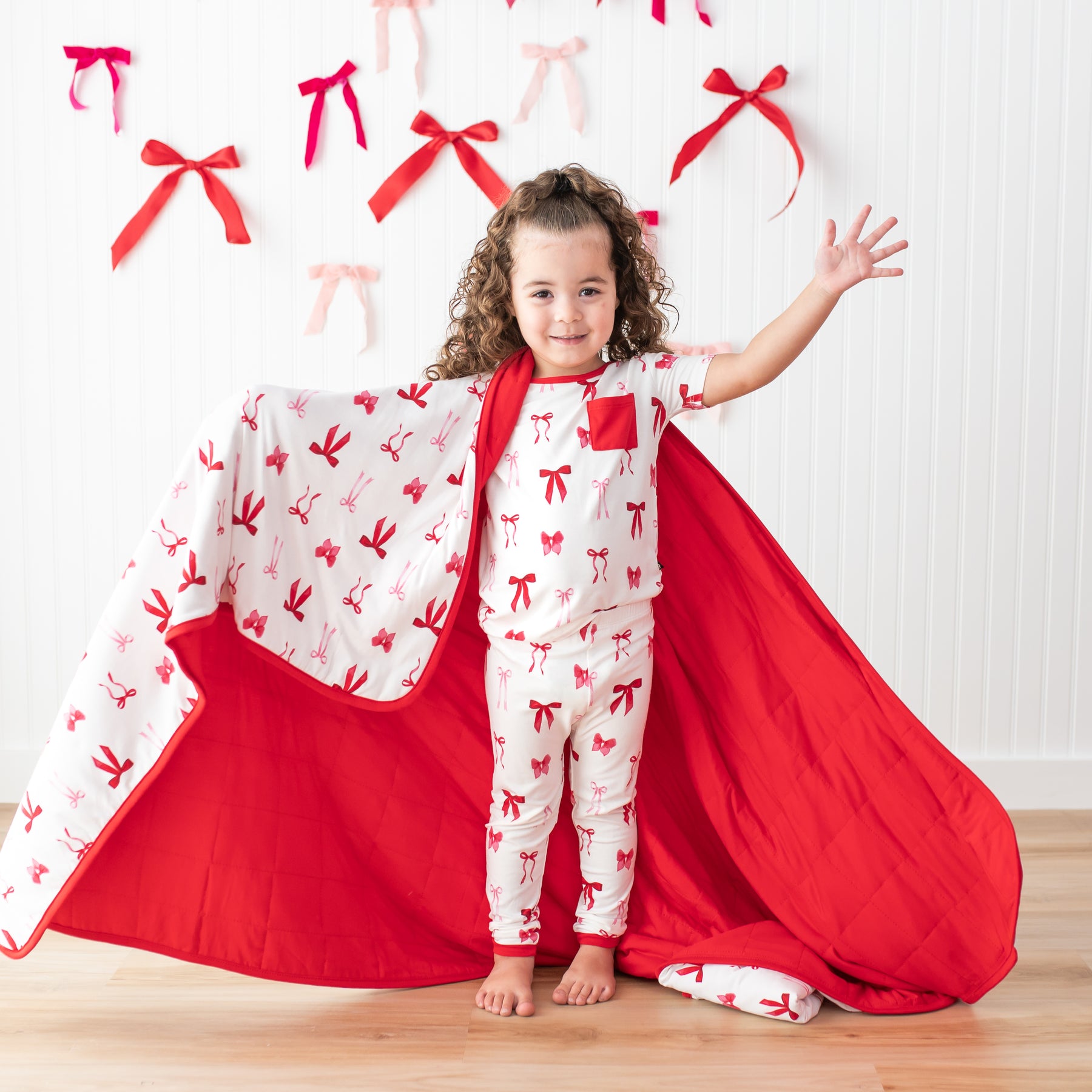 Young girl wearing the Short Sleeve with Pants Pajamas in Small Love Bow with the matching toddler blanket around her shoulders