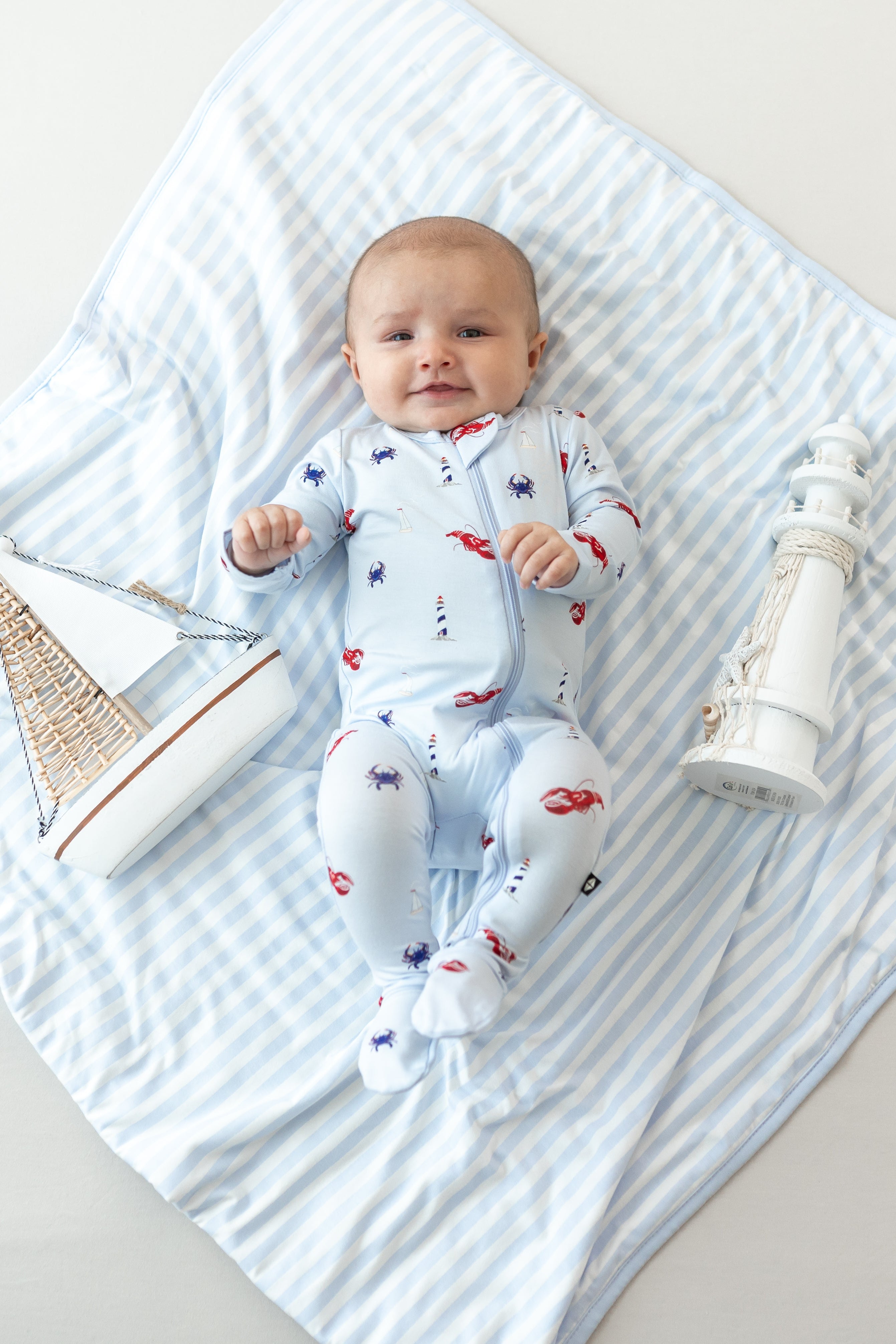Infant laying on a Baby Blanket in Small Mist Stripe TOG 1.0 wearing Harbor Zippered Footie pajamas