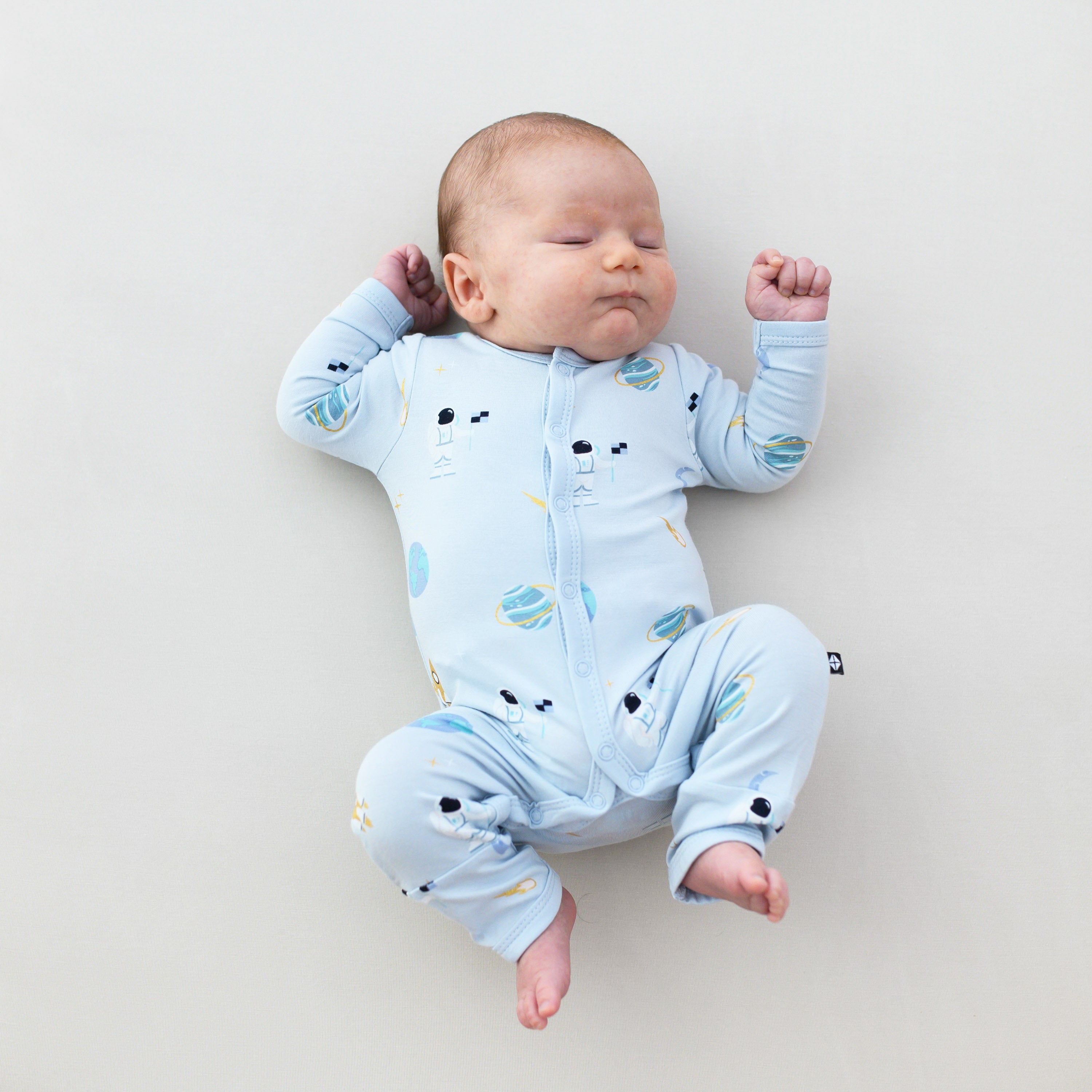 baby laying down wearing ice space snap romper