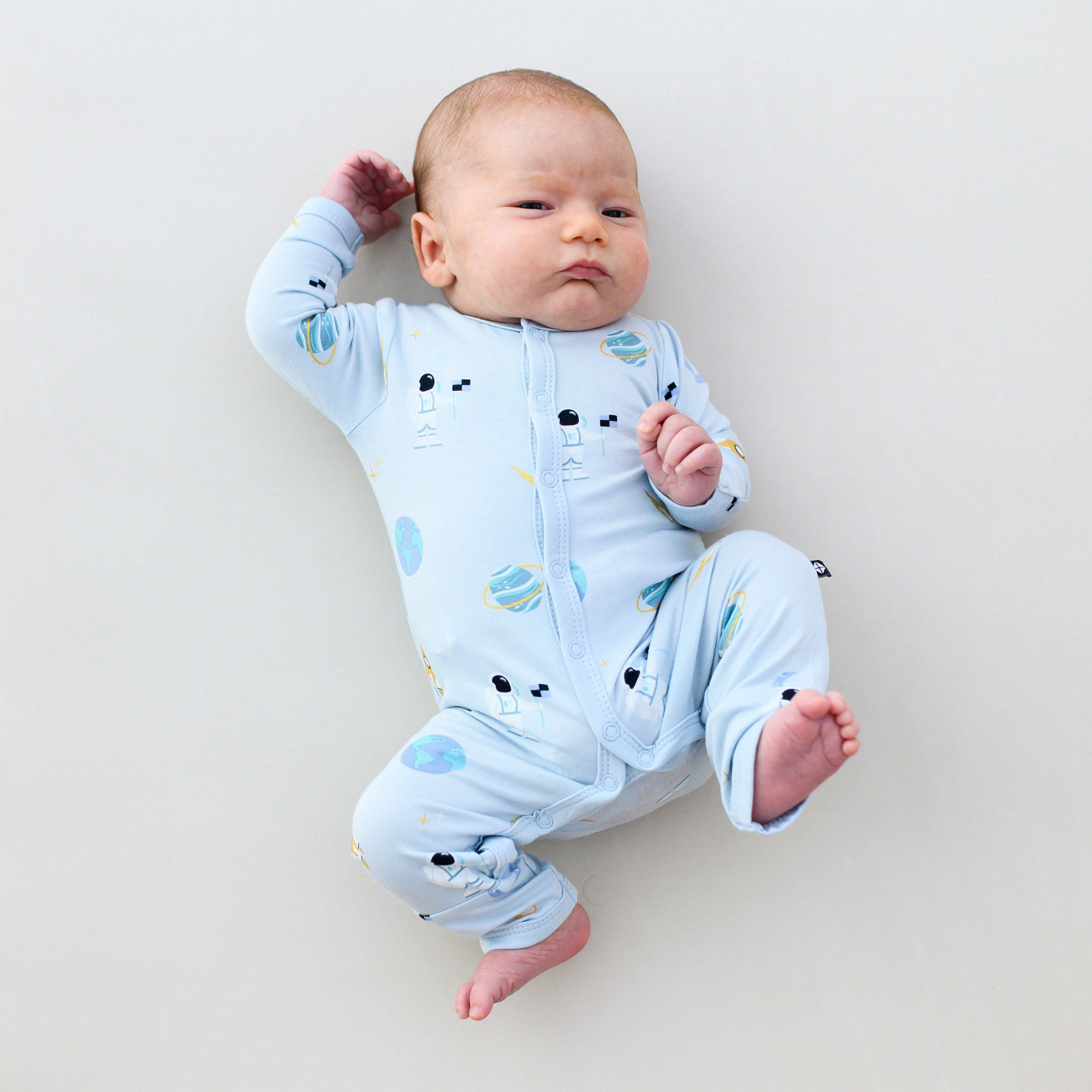 baby laying and stretching wearing ice space snap romper