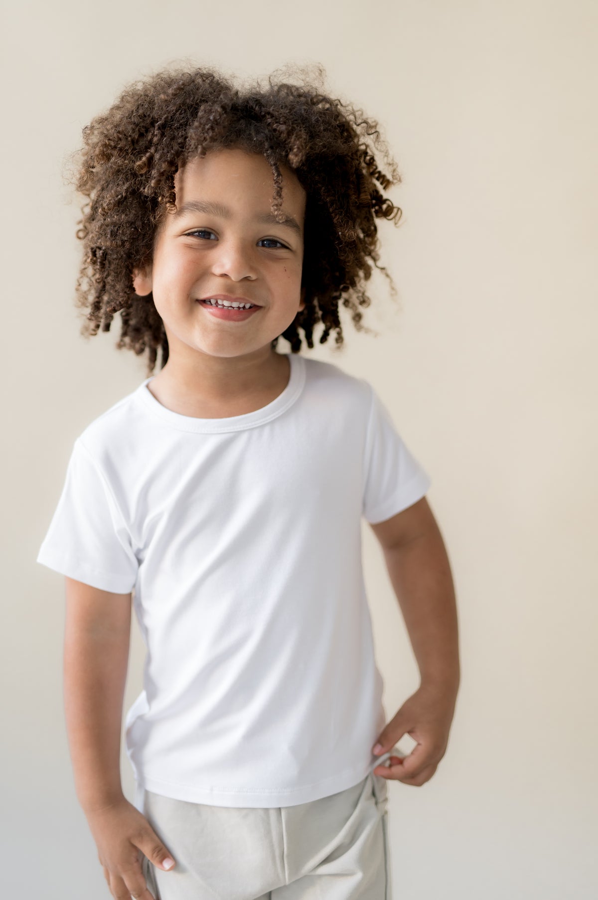Young boy wearing the Toddler Basic Tee in Snow with light colored pants