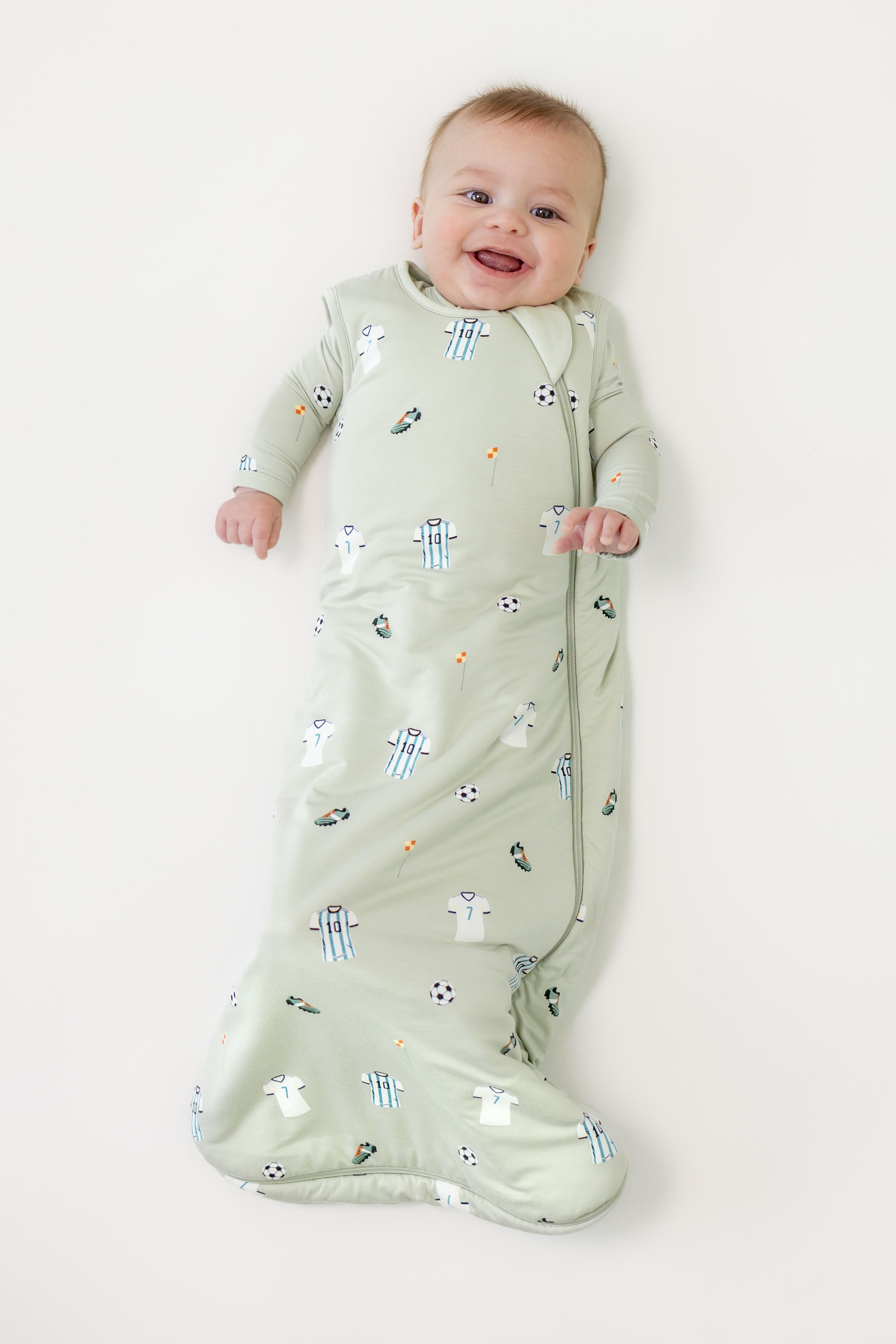 Baby wearing Soccer print sleep bag on a beige background