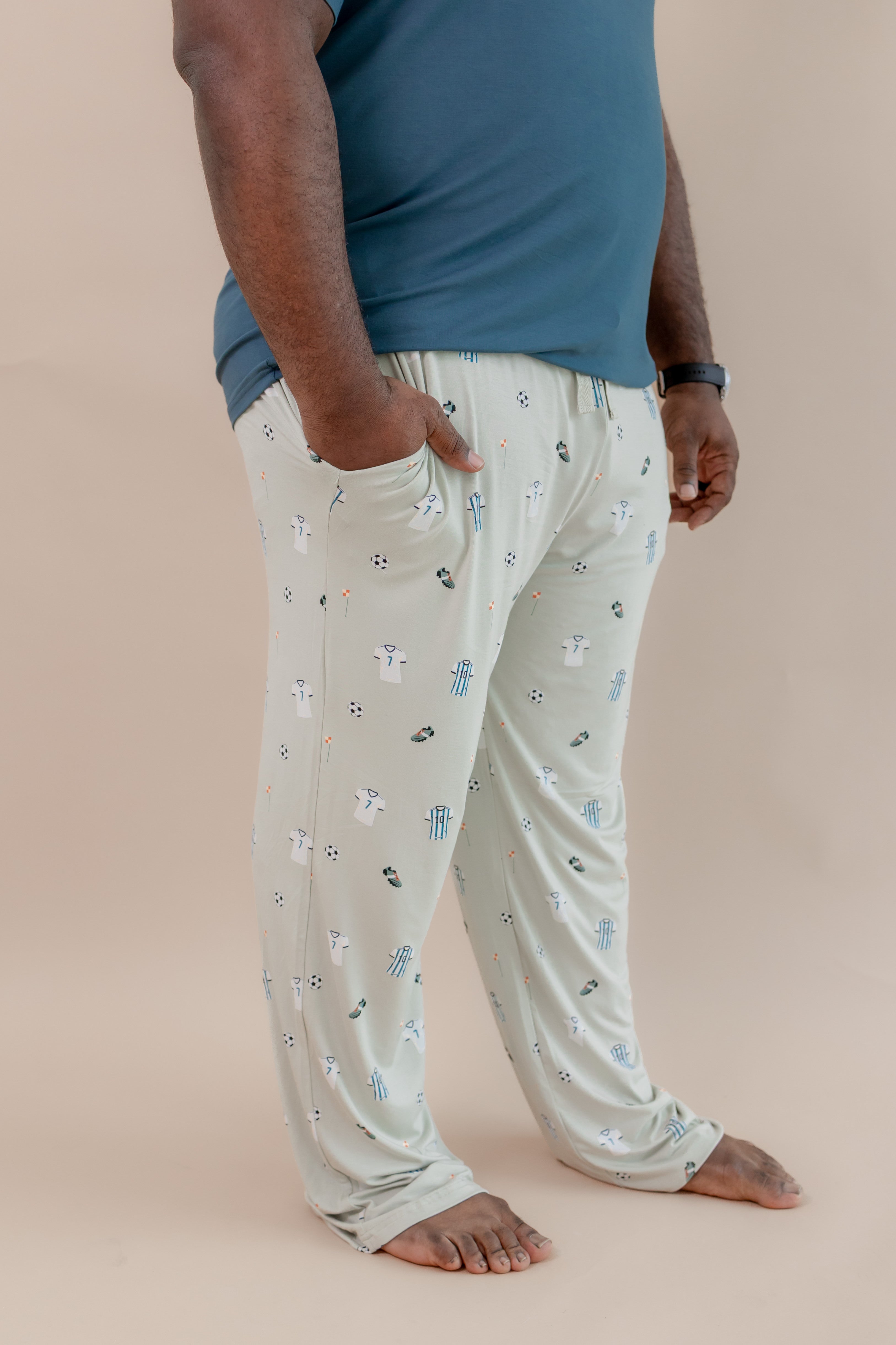 Side view of Men's Lounge pant with pockets in Soccer print under an Atlantic T-shirt on a beige background