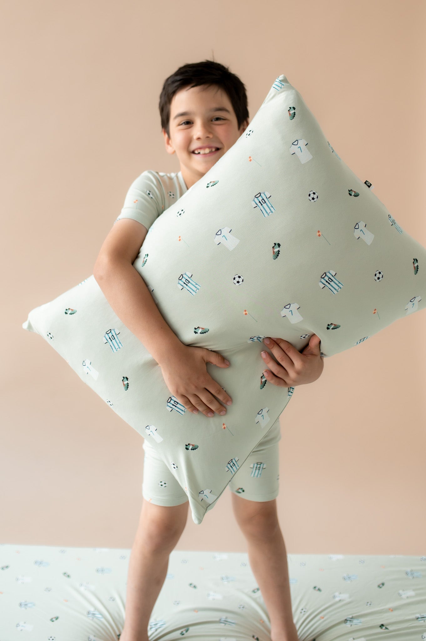 child holding a pillow with a soccer pattern