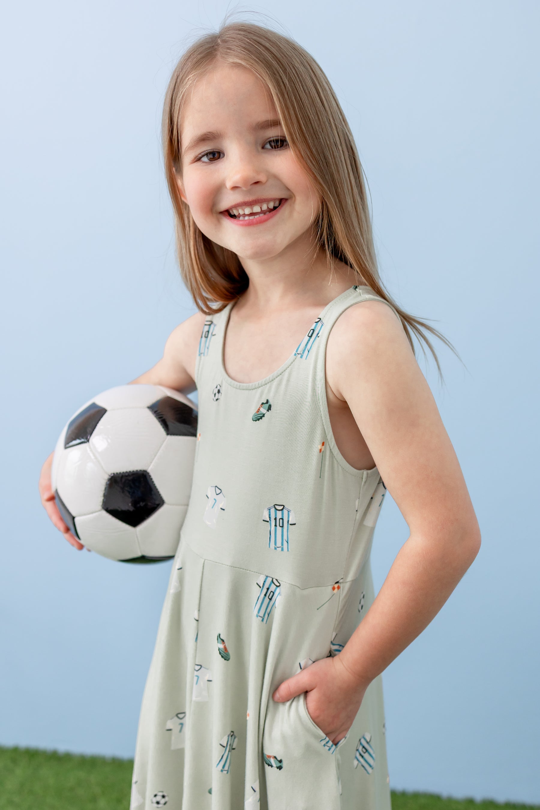 Child holding soccer ball wearing Tank Twirl dress in Soccer print