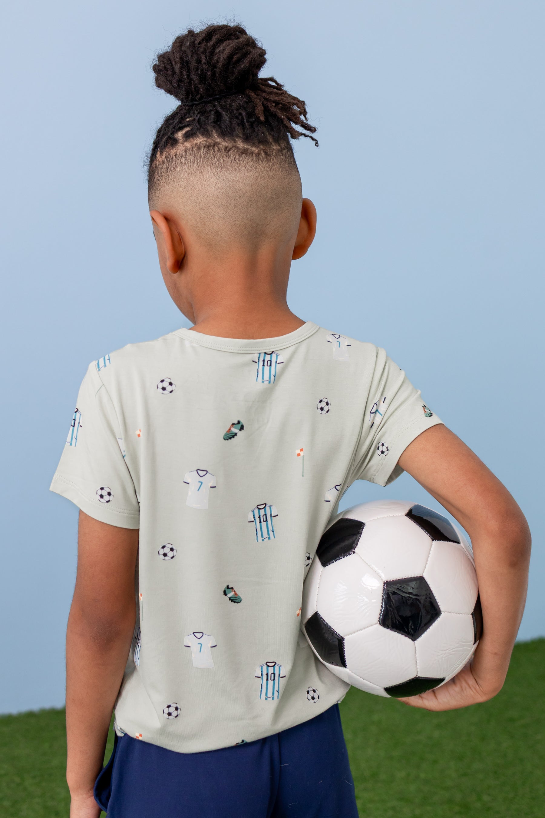 Back side of Toddler Basic Tee in Soccer print over navy shorts
