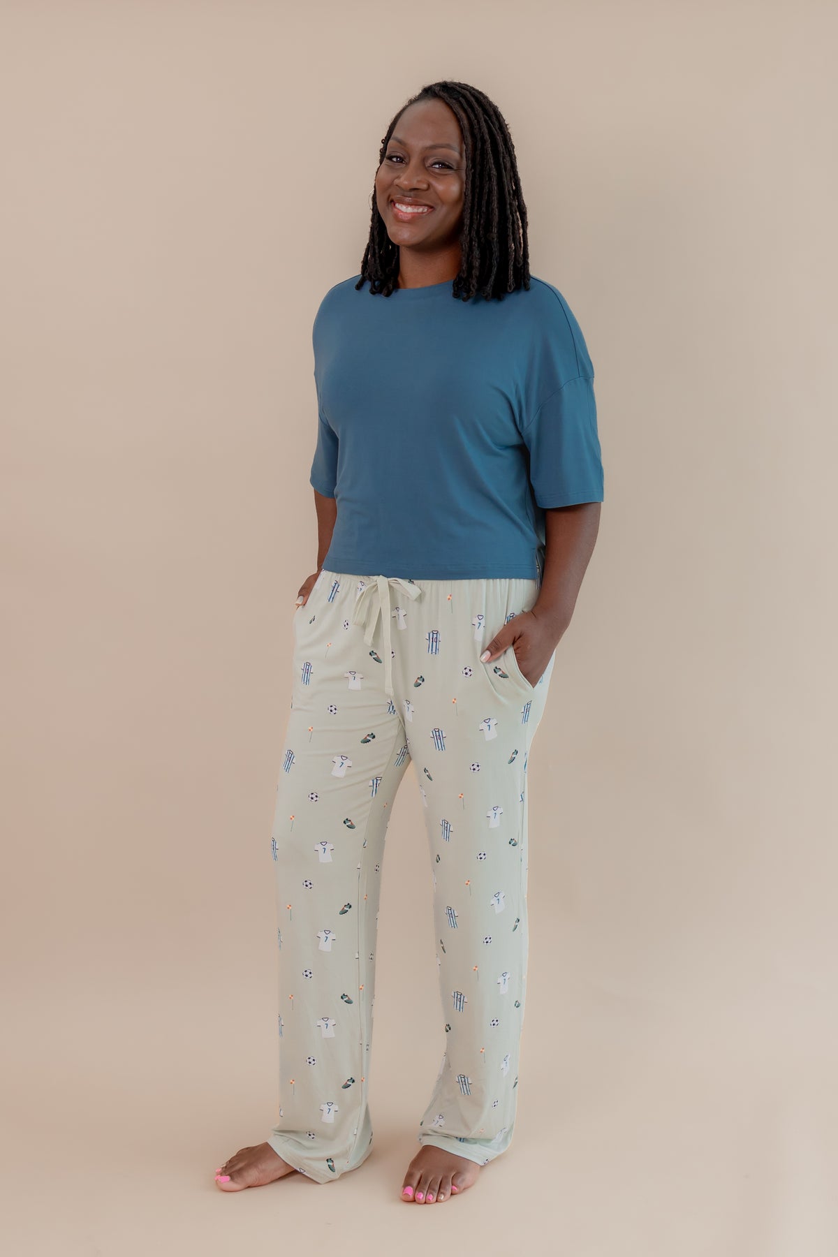 Model wearing Women's Lounge pant in Soccer print under an Atlantic T-shirt on a beige background