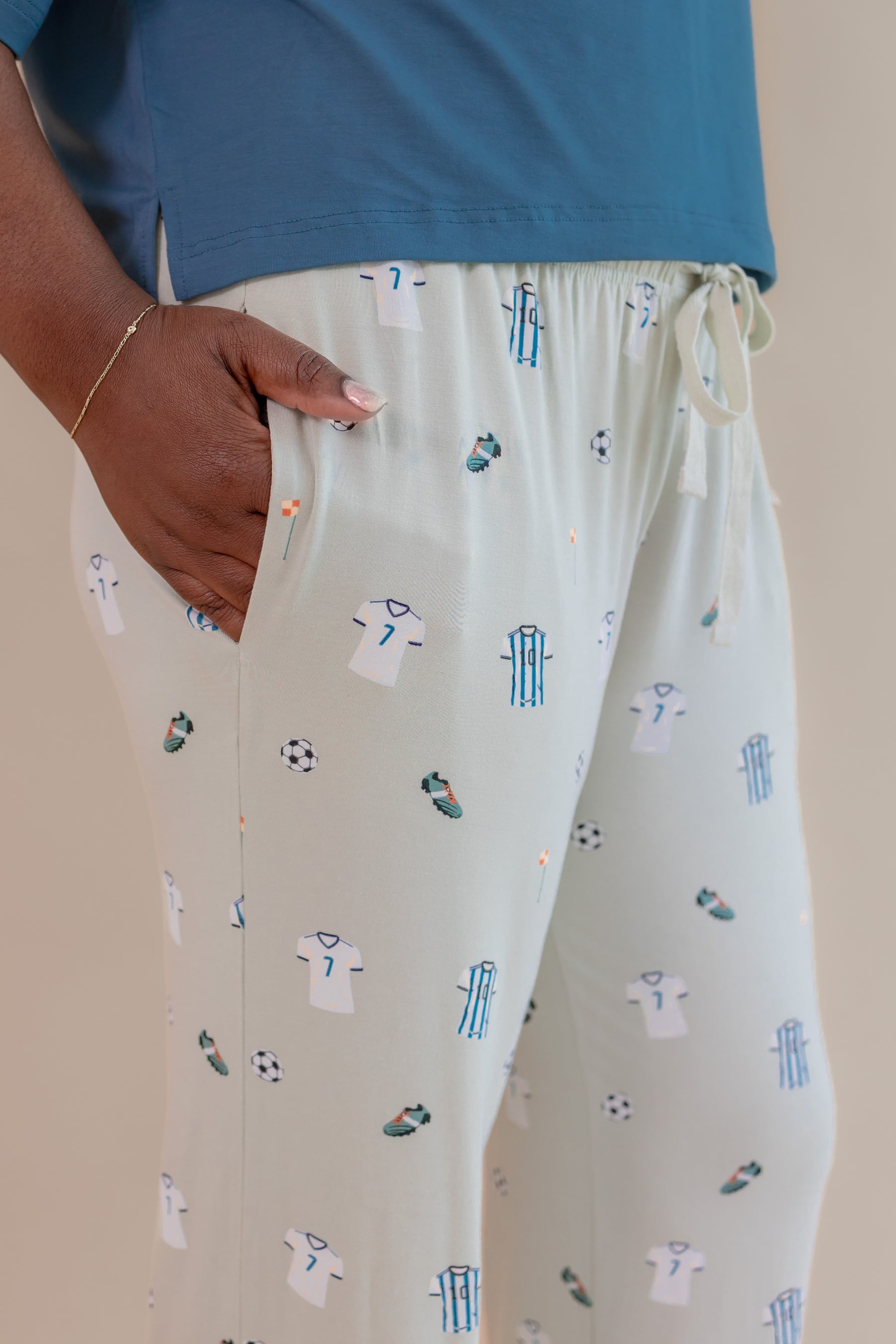 Model wearing Women's Lounge pant with pockets in Soccer print under an Atlantic T-shirt on a beige background