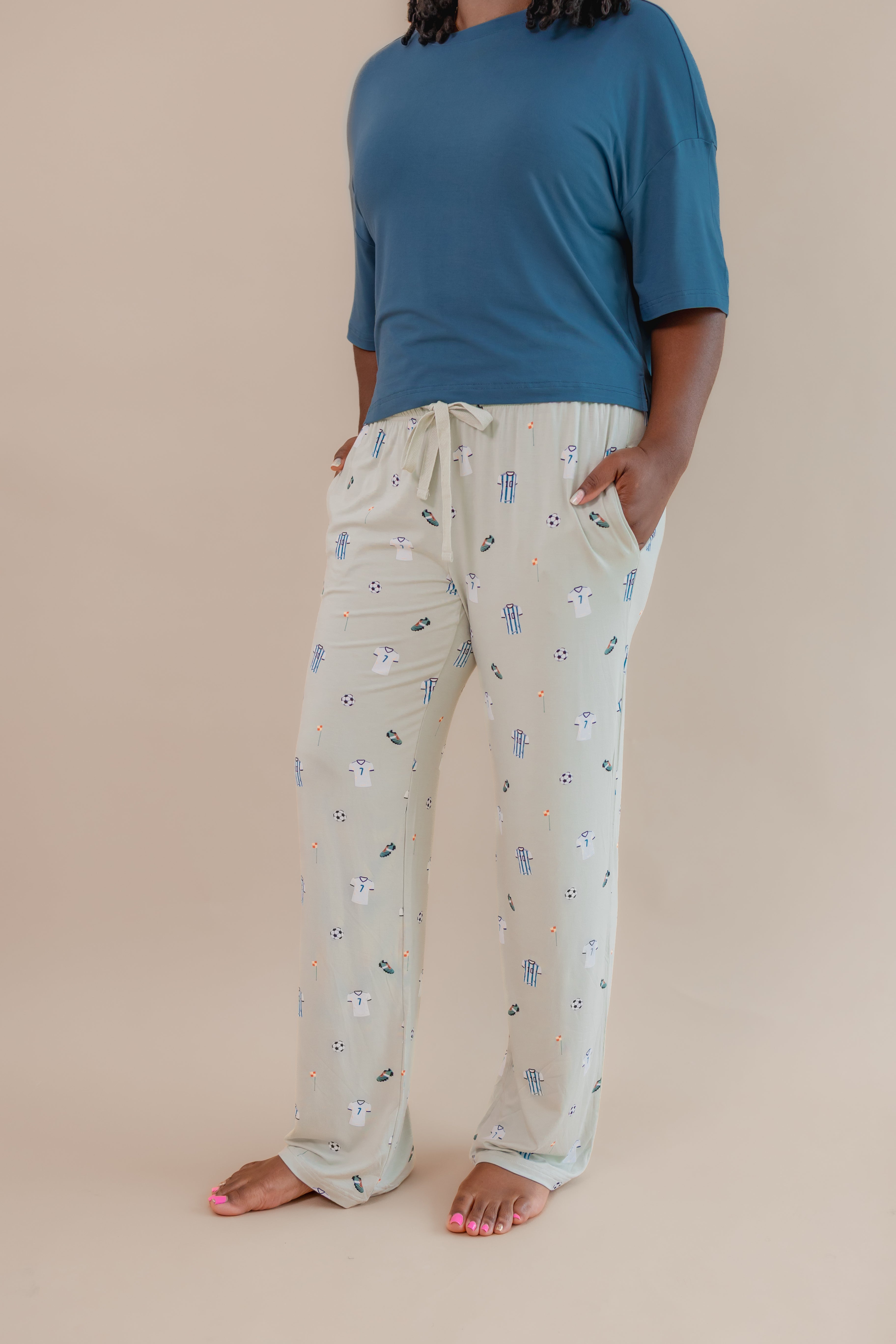 Side view of Women's Lounge pant with pockets in Soccer print under an Atlantic T-shirt on a beige background