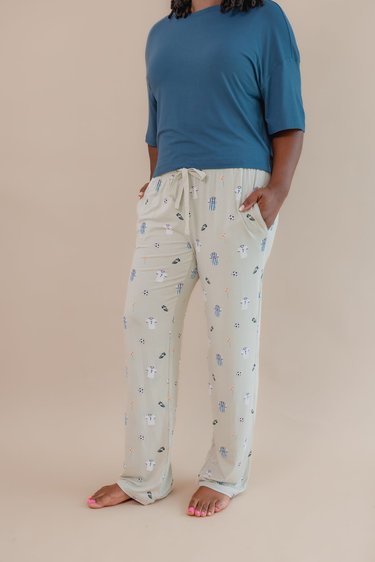 Side view of Women's Lounge pant with pockets in Soccer print under an Atlantic T-shirt on a beige background