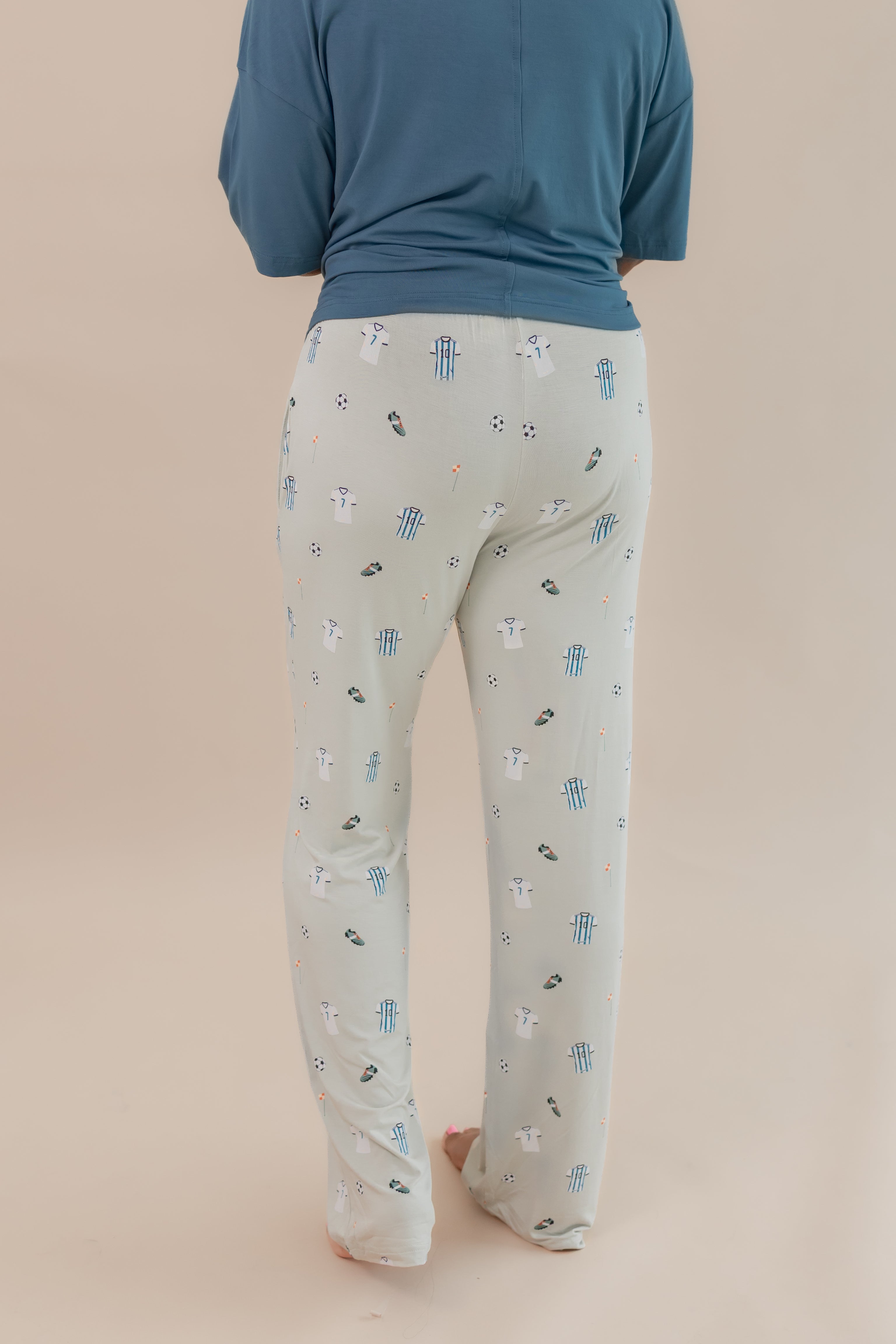 Back side of Women's Lounge pant in Soccer print under an Atlantic T-shirt on a beige background