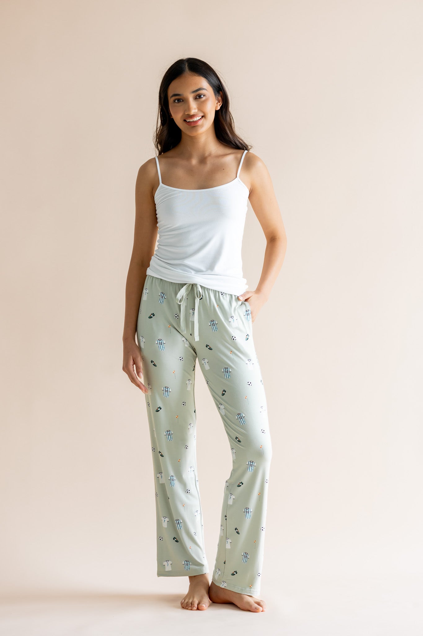 Model wearing Women's Lounge pant in Soccer print under white camisole on a beige background