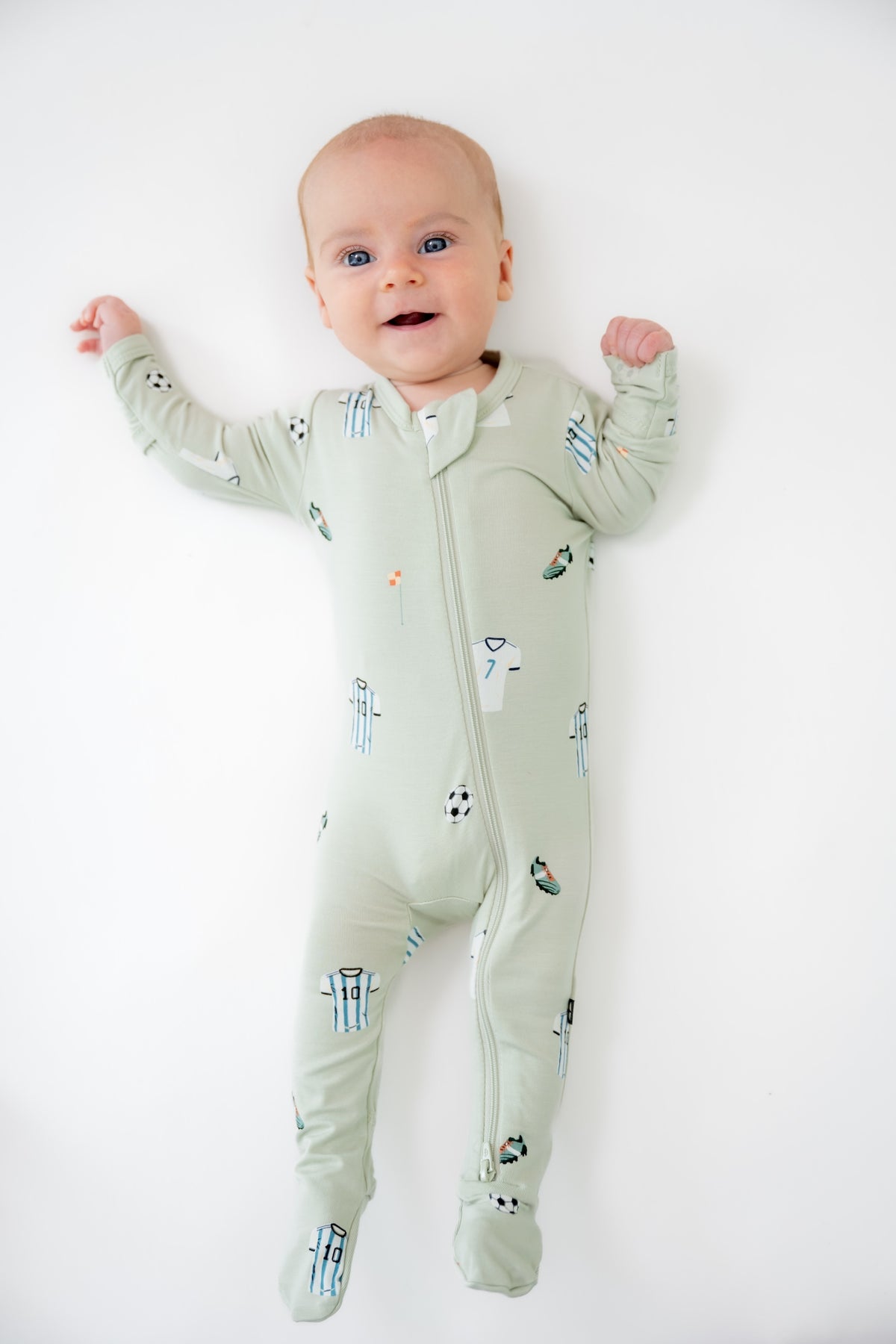 Baby wearing Soccer print zippered footie on a white background