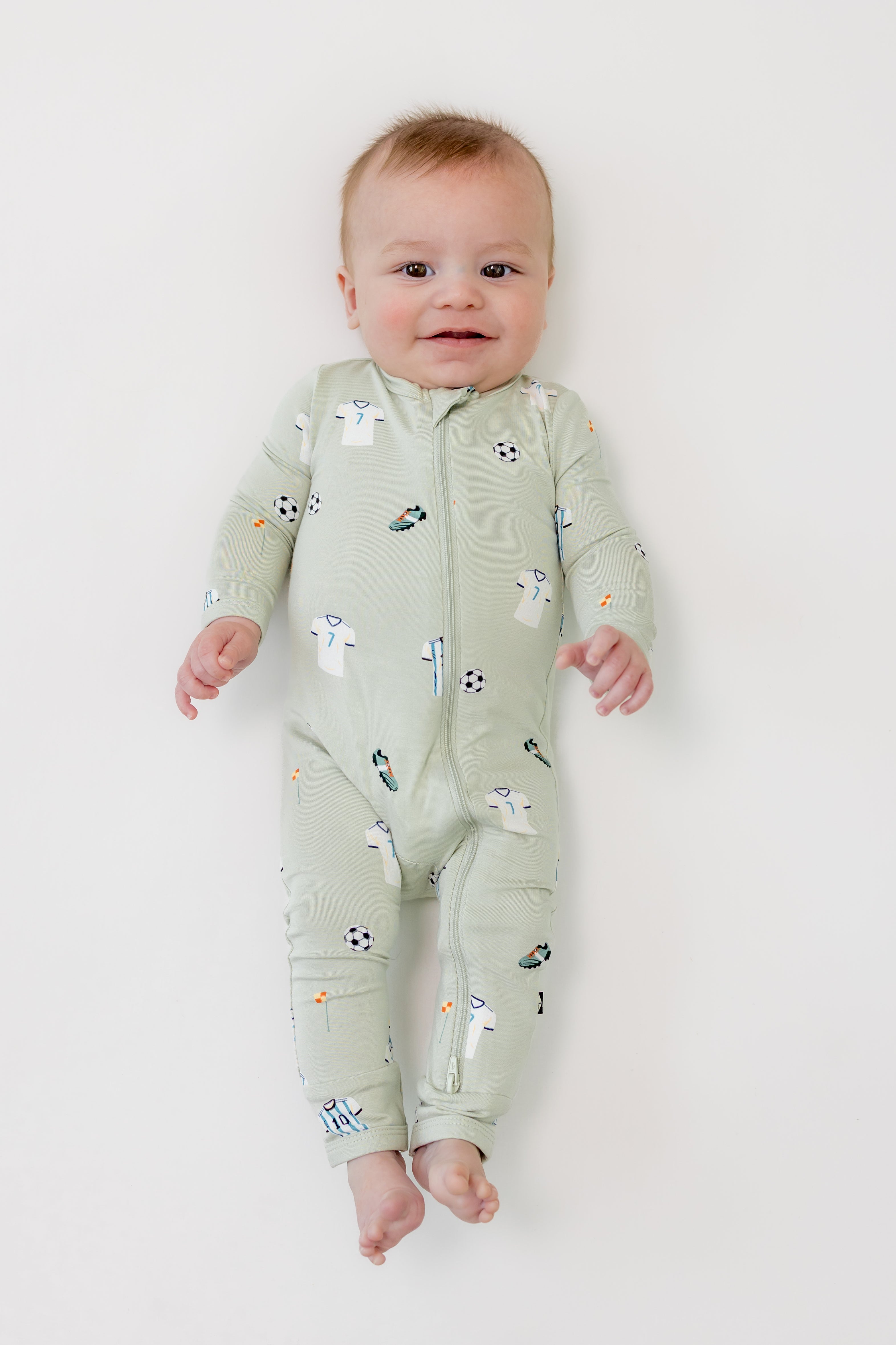 Baby wearing Soccer print zippered romper on a white background
