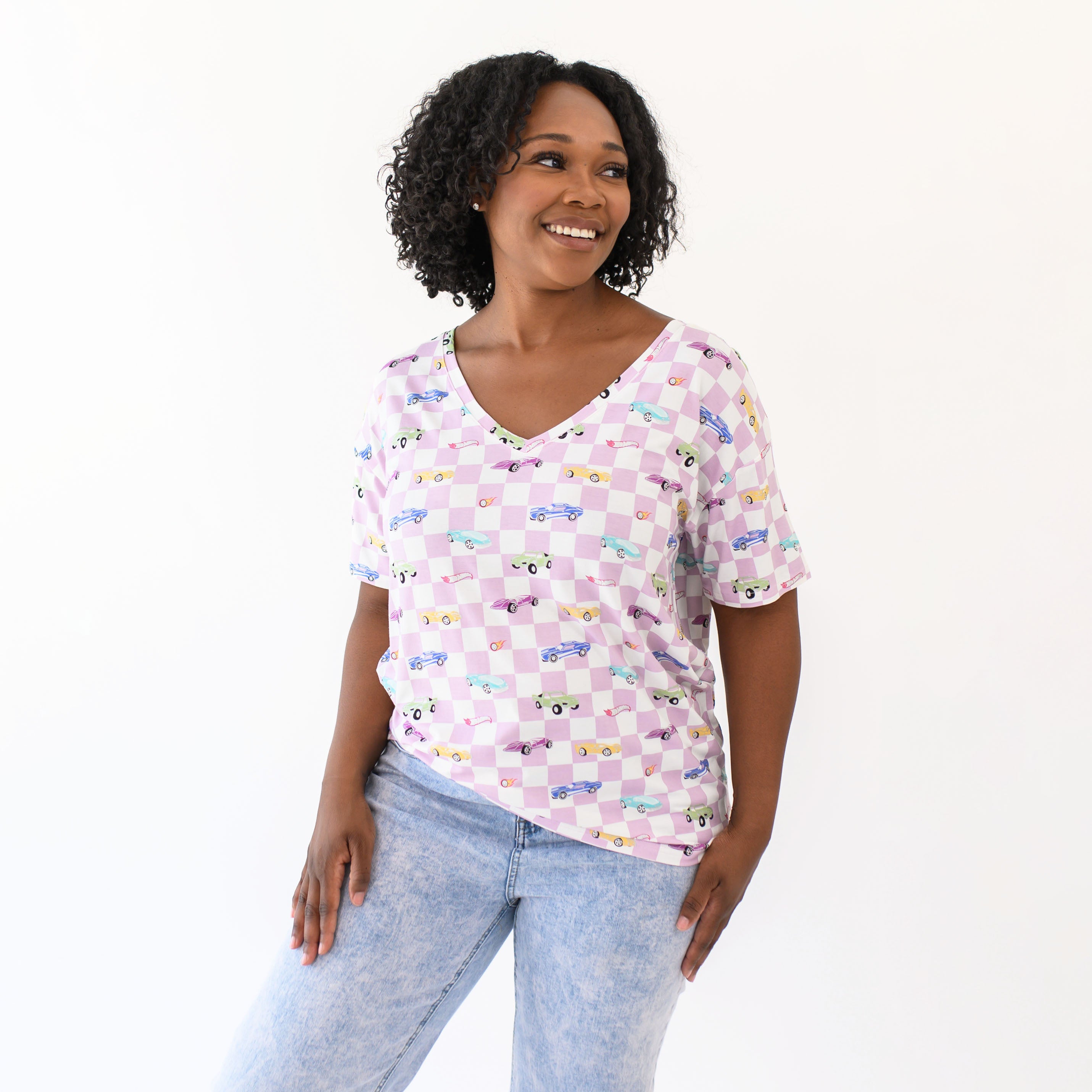 Smiling female modeling the Women's Relaxed Fit V-Neck in Sparkles and Speed paired with light wash jeans
