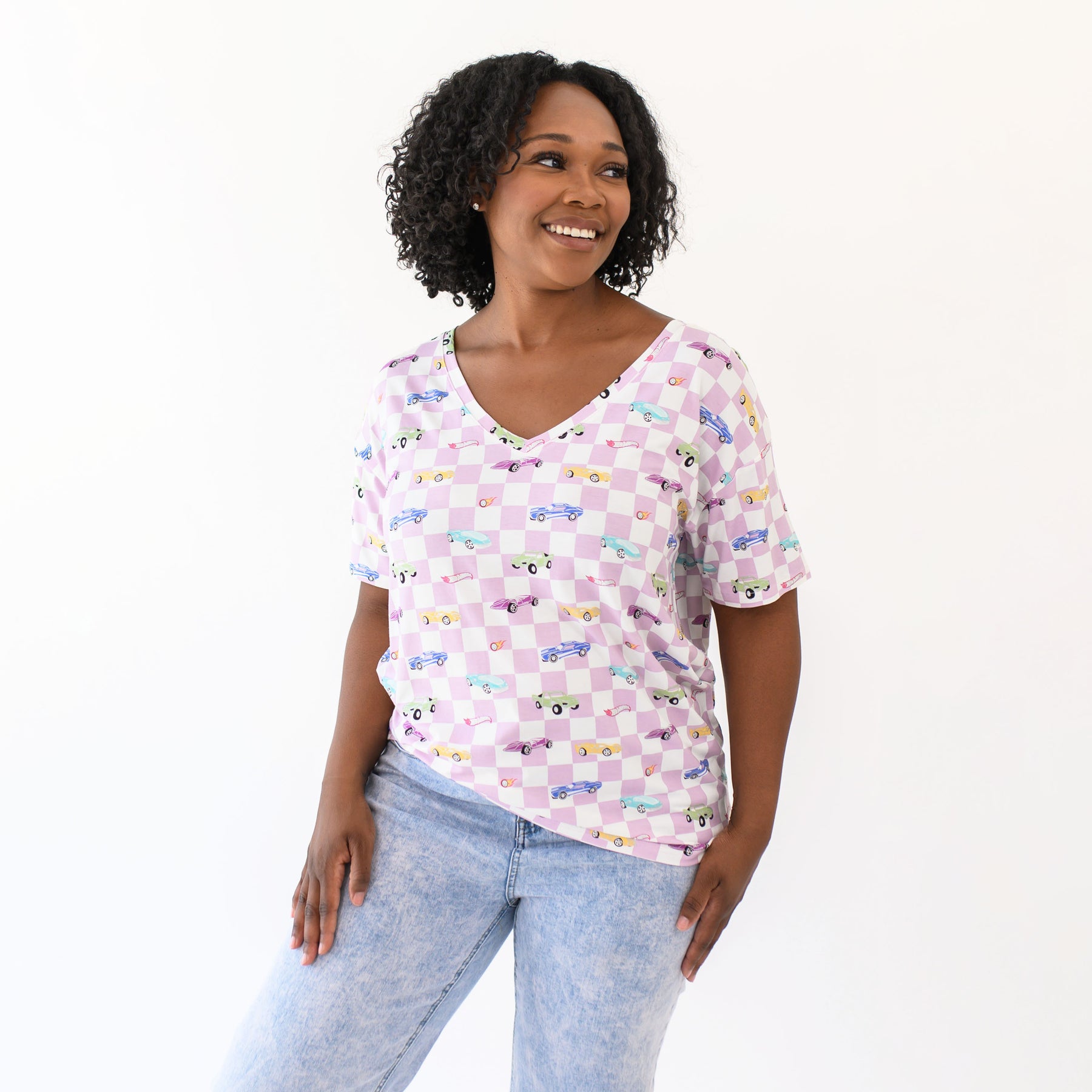 Smiling female modeling the Women's Relaxed Fit V-Neck in Sparkles and Speed paired with light wash jeans