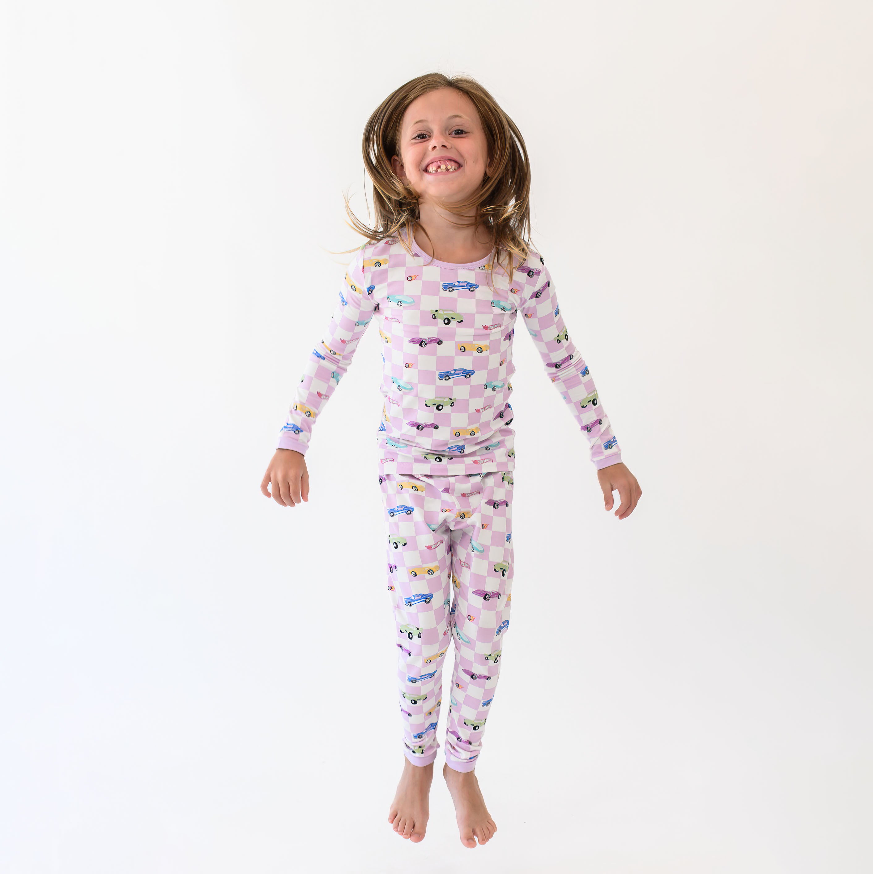Young girl jumping wearing the Long Sleeve Pajamas in Sparkles and Speed