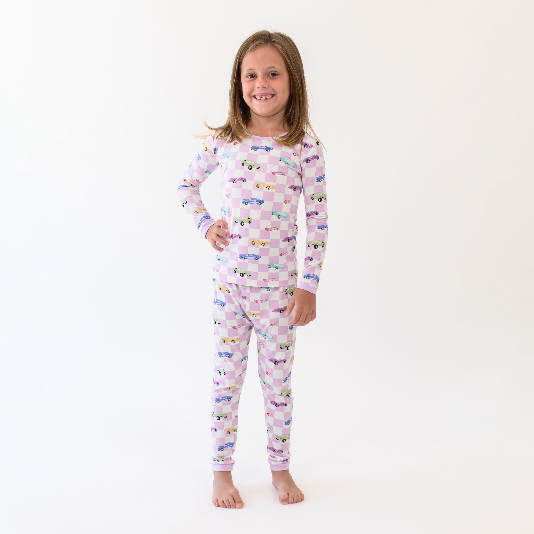 Smiling girl standing with one hand on hip wearing the Long Sleeve Pajamas in Sparkles and Speed