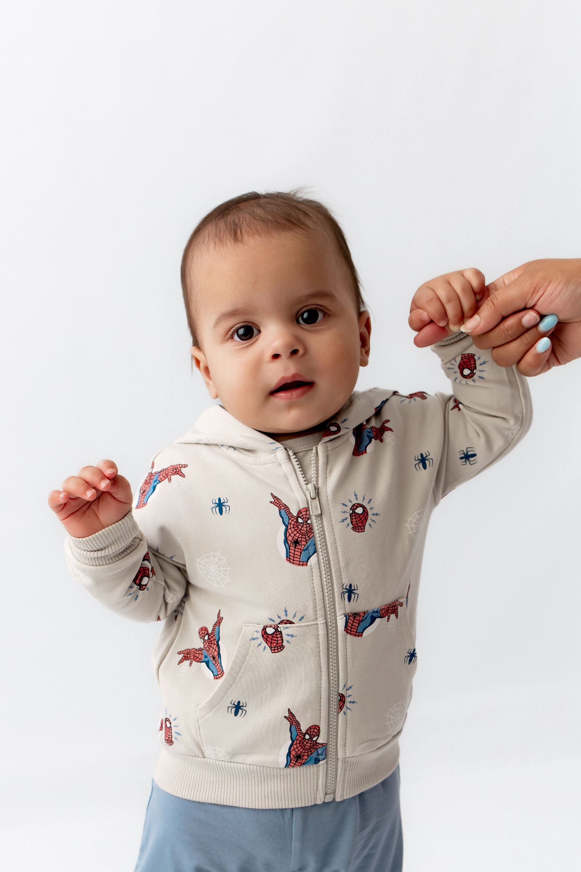 toddler standing up wearing a spiderman jacket.