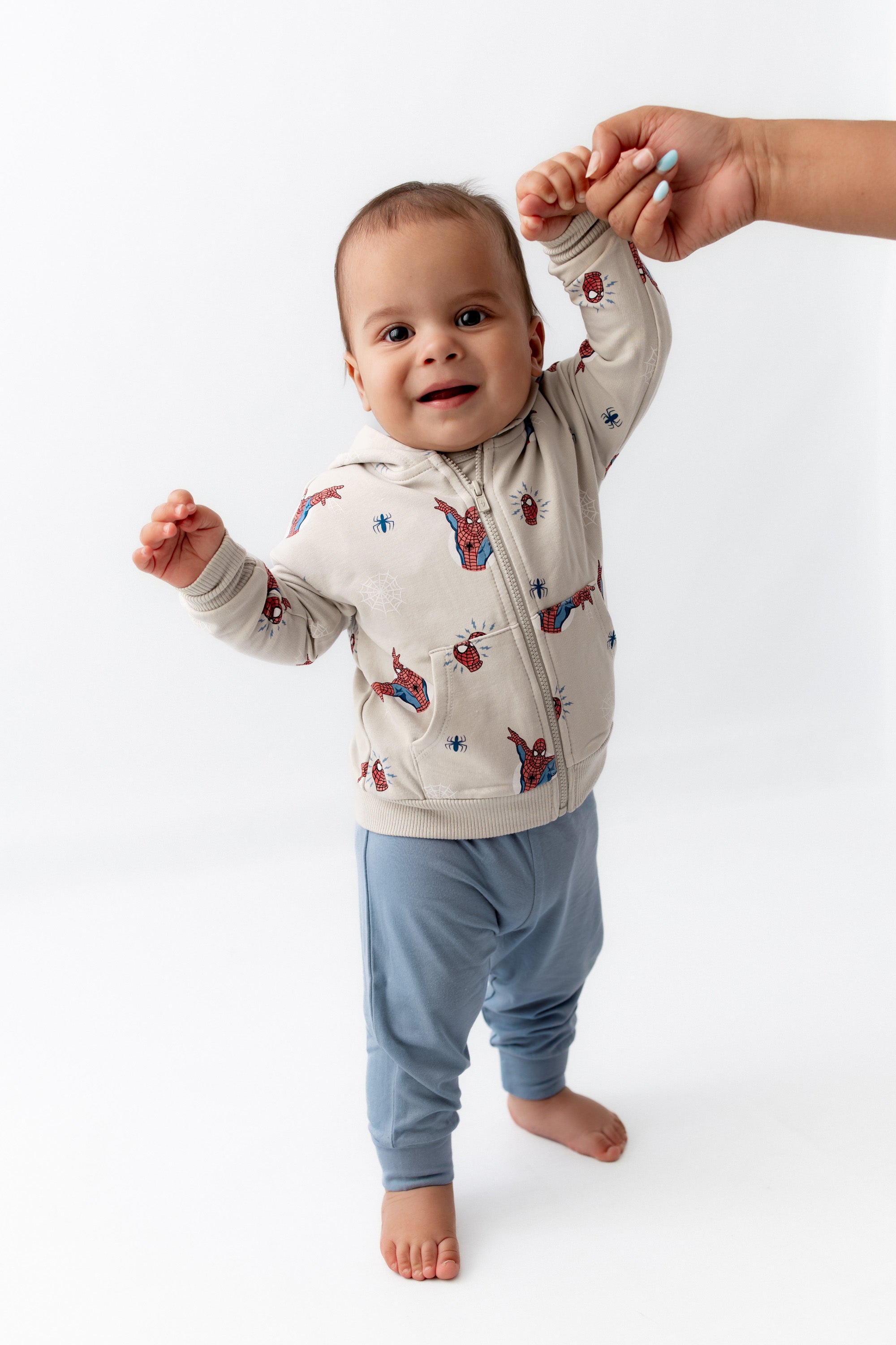Toddler standing smiling in a zippered jacket in spiderman.