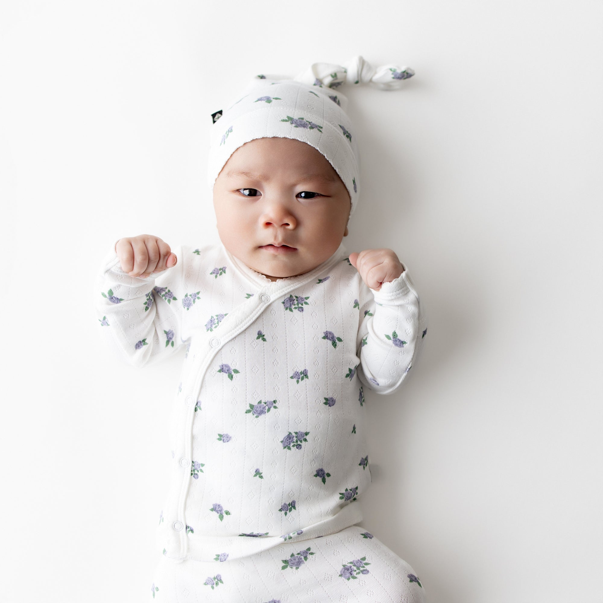 Close up of a newborn wearing the Pointelle Take Me Home Set with Cap in Spray Rose showing the picot trim