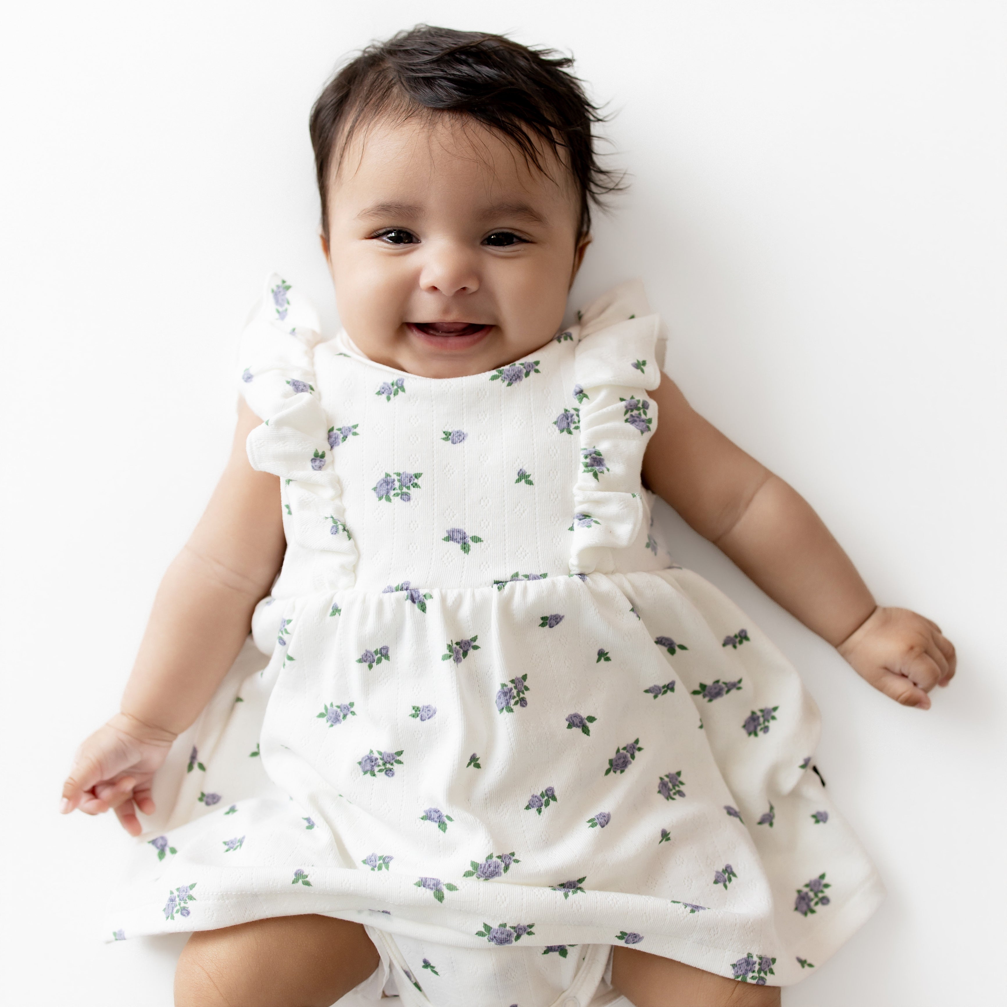 Baby wearing a white floral dress on a white background