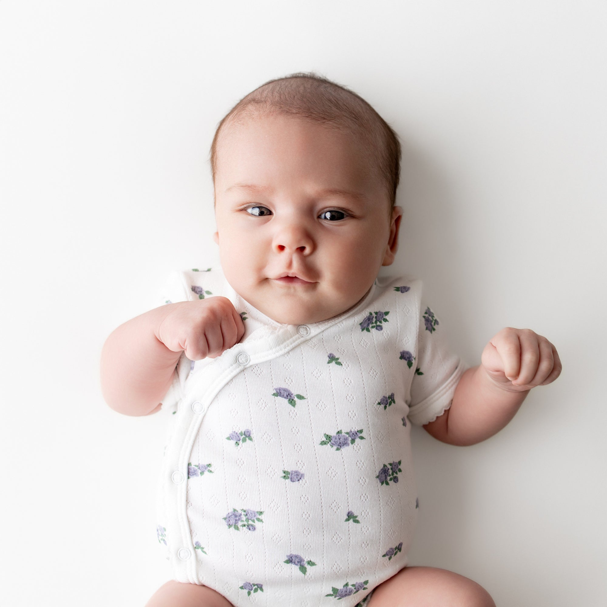 Close up of a newborn wearing the Pointelle Kimono Bodysuit in Spray Rose showing the picot trim
