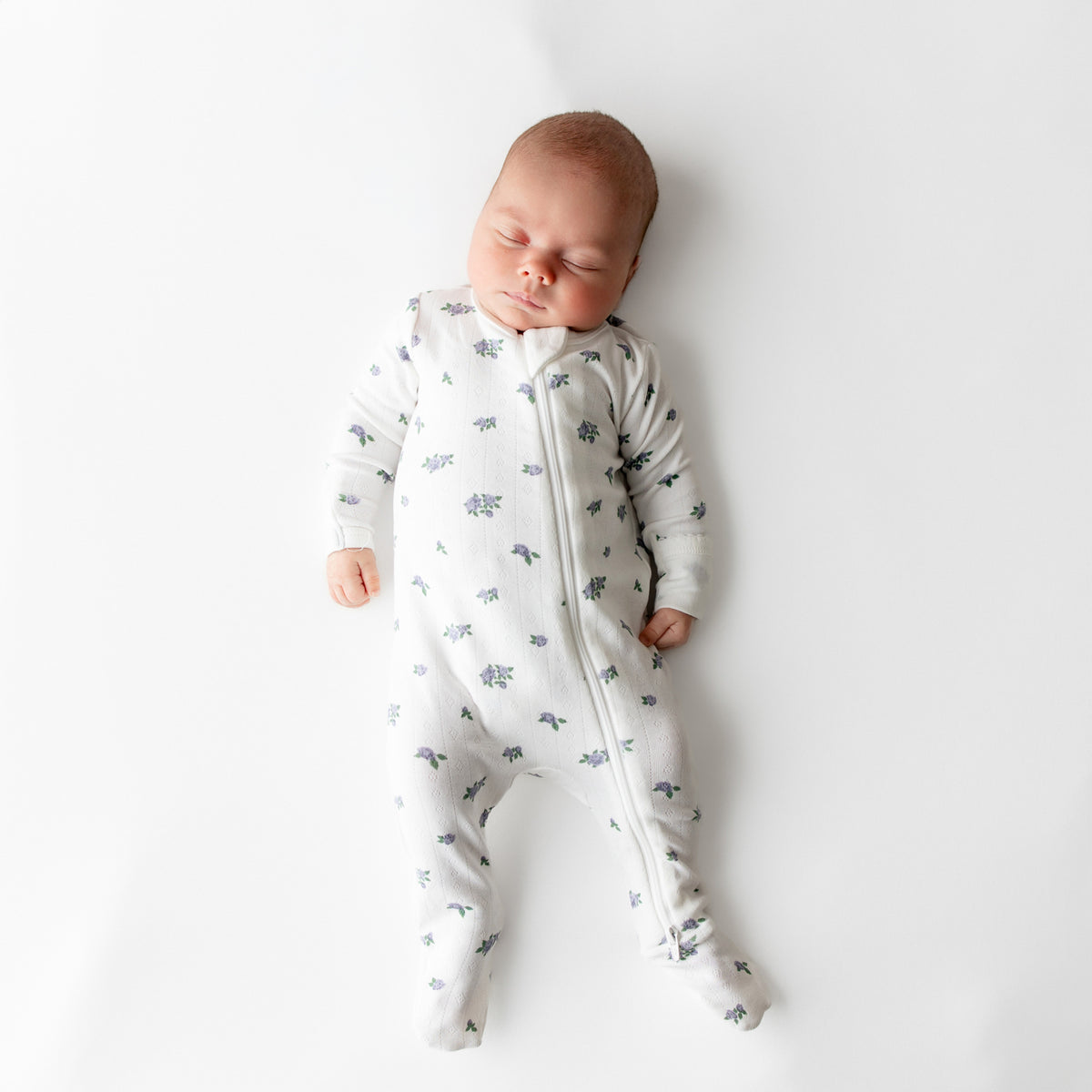 Sleeping newborn wearing the Pointelle Zippered Footie in Spray Rose